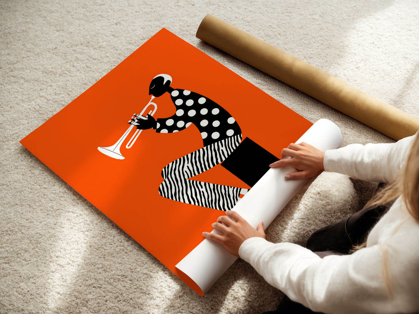 Person unrolling a poster with a design of a person playing a trumpet on an orange background.