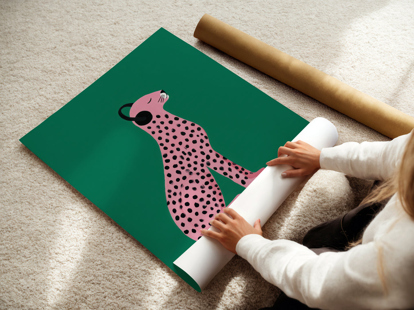 Person unrolling a statement wall art green poster with a pink panther design on a beige carpet.