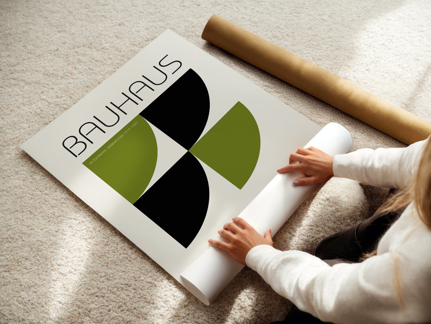 Person unrolling a Bauhaus poster on a carpeted floor