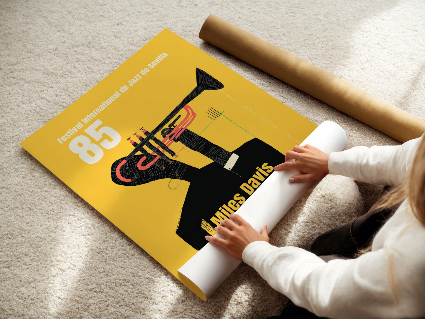 Person unrolling a poster featuring Miles Davis on a beige carpet