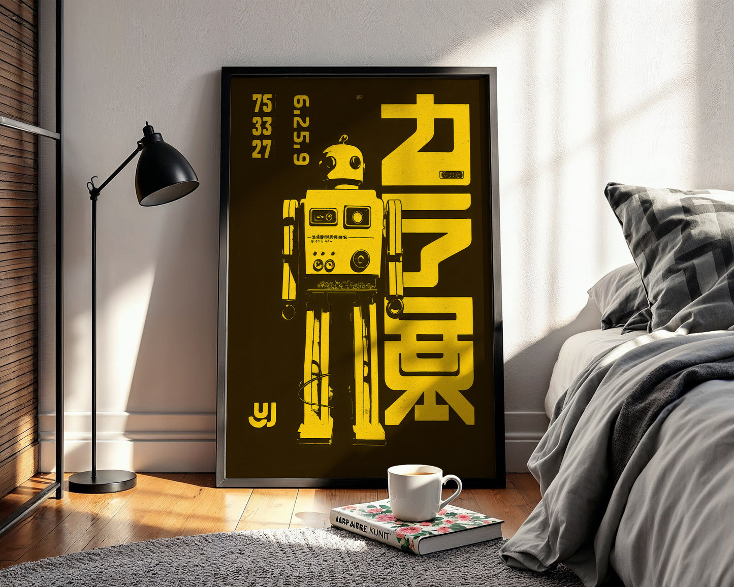Framed robot poster on a wall in a bedroom with a cup and book on a table.