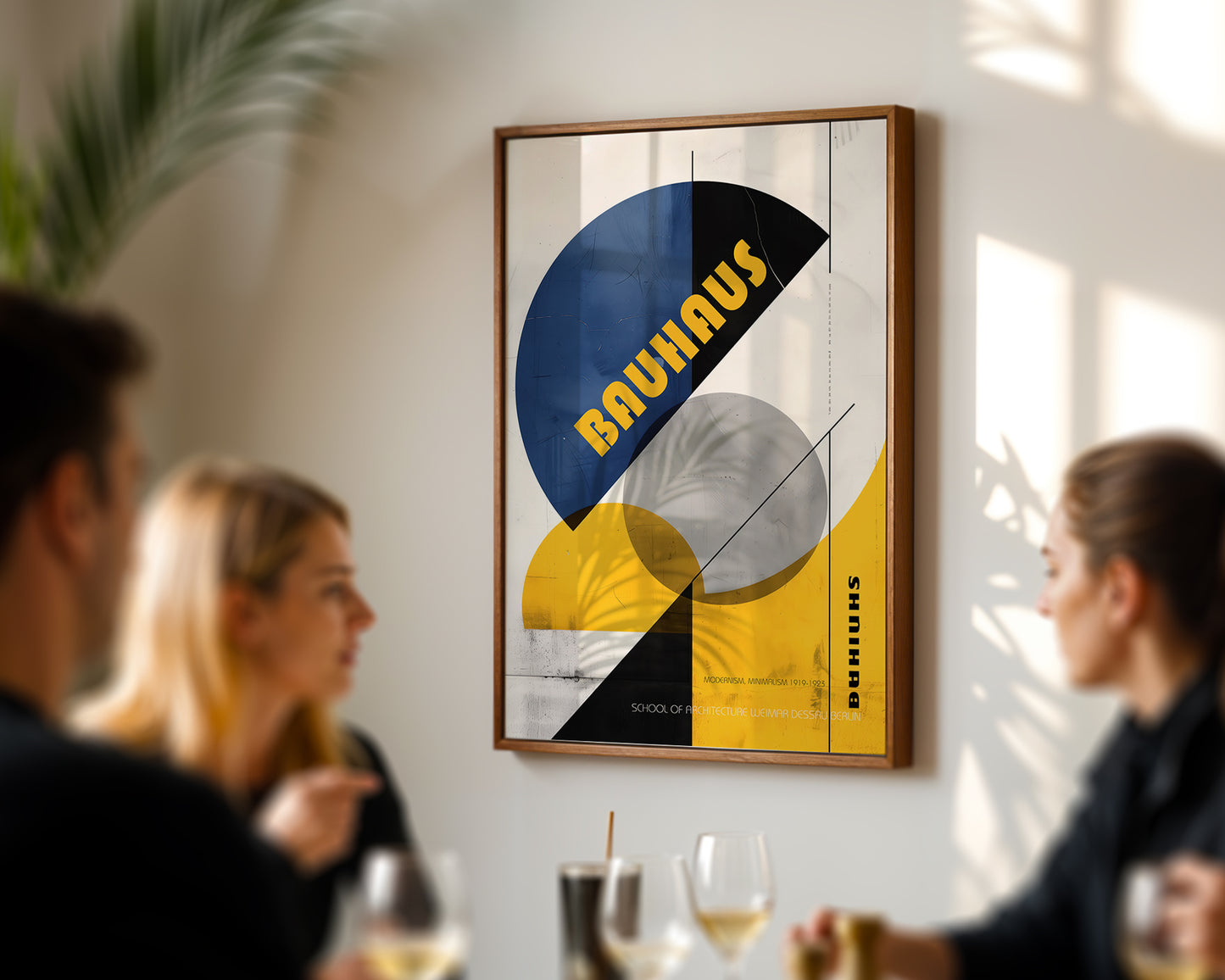 Framed Bauhaus art on a wall with young people at a dining room table
