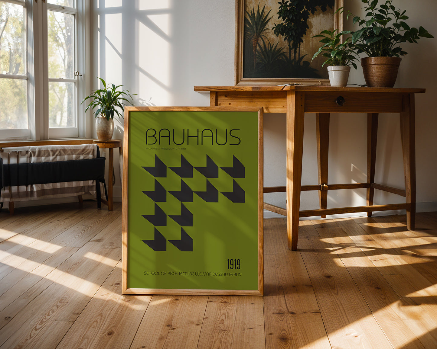 Framed green  Bauhaus poster on a wooden floor with a table and plants in the background