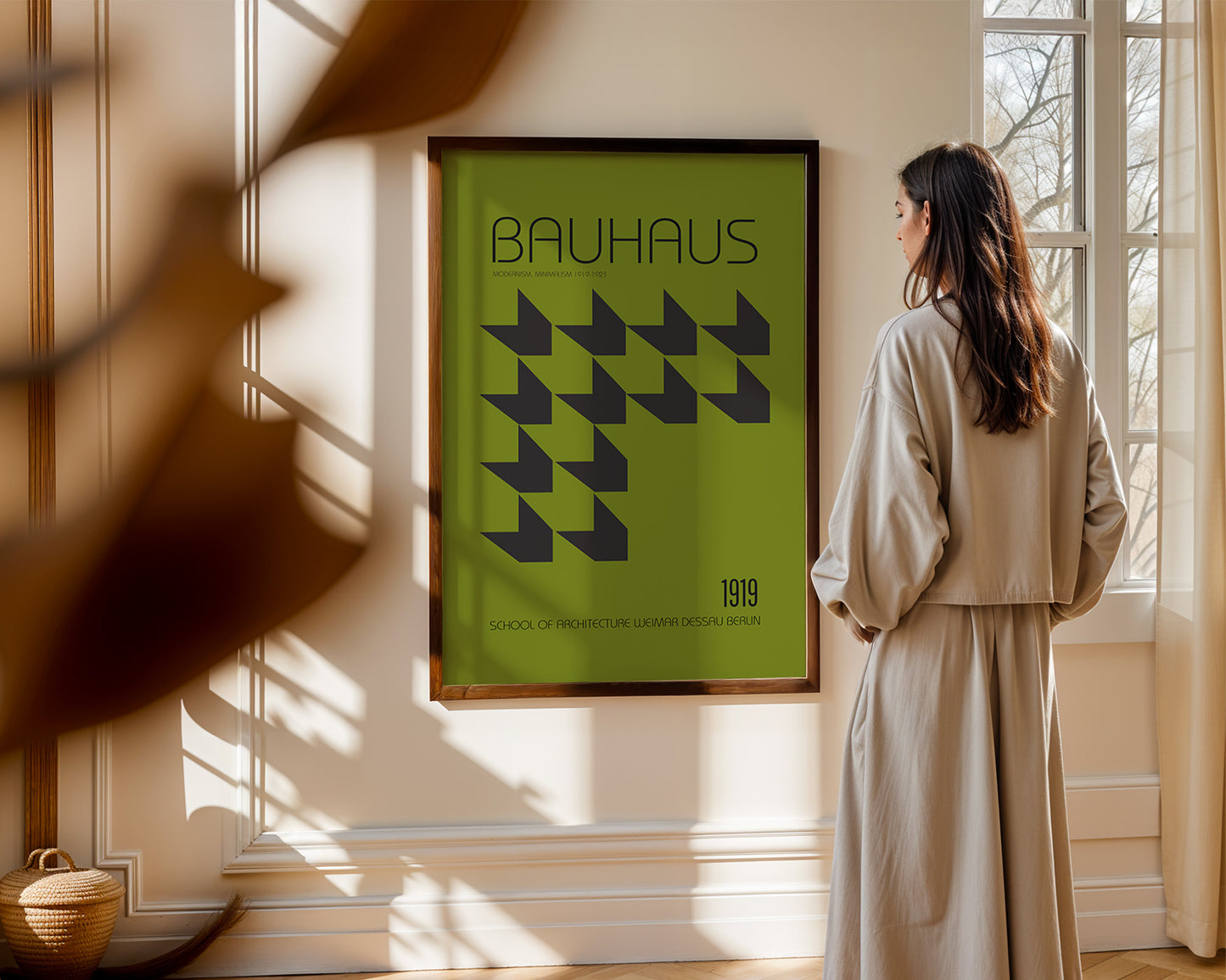 Woman standing in a room with an olive green Bauhaus poster on the wall