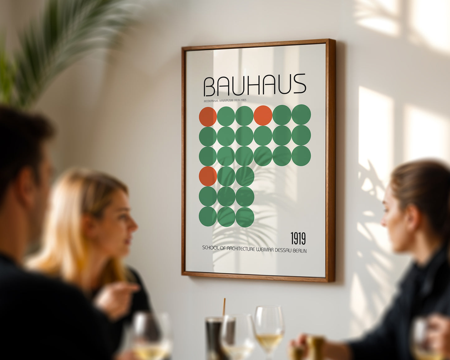 Framed Bauhaus poster on a wall with people sitting at a table below.