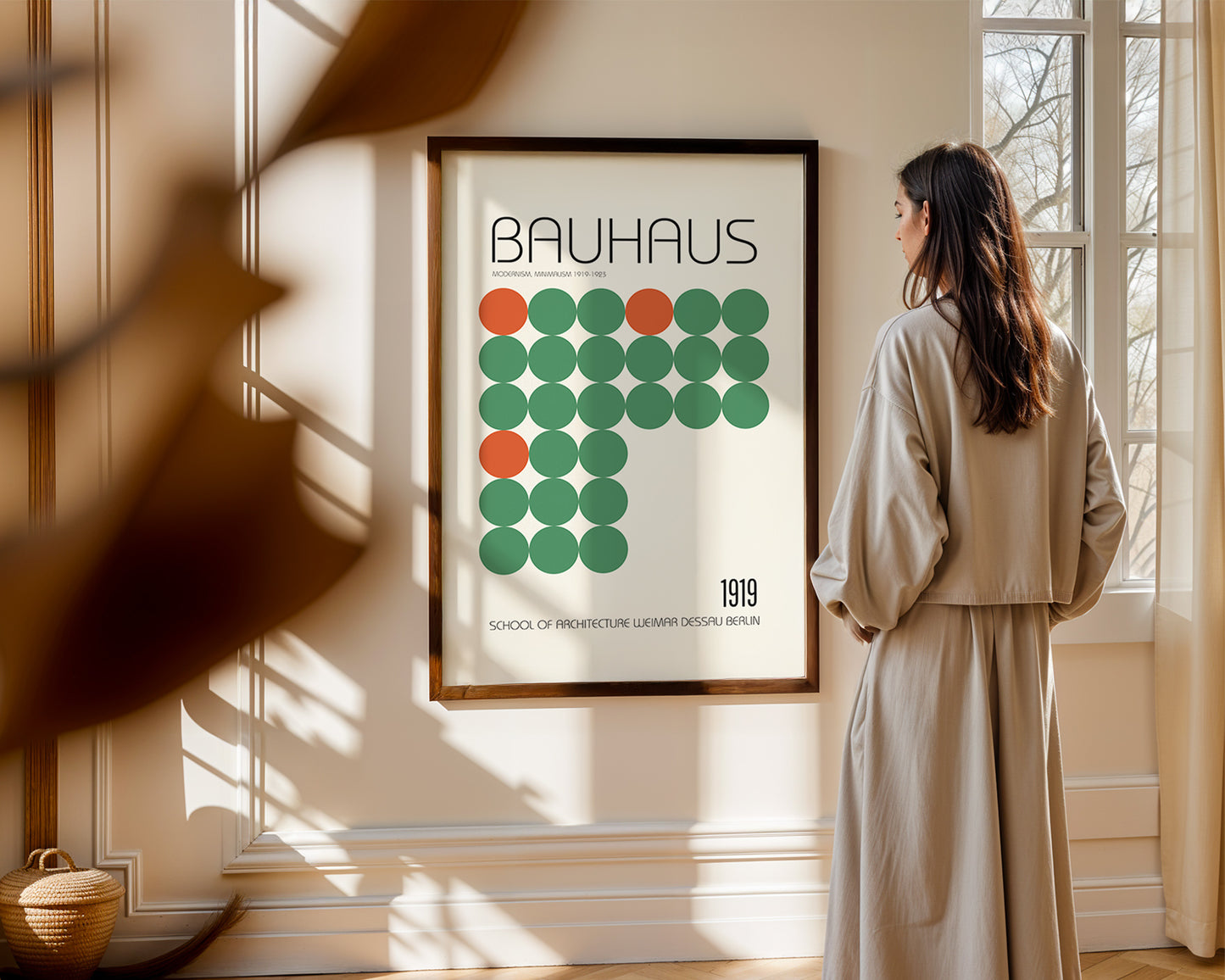 Woman standing in a room looking at a Bauhaus poster on the wall.Mid-century modern wall art print featured in neutral interior design space