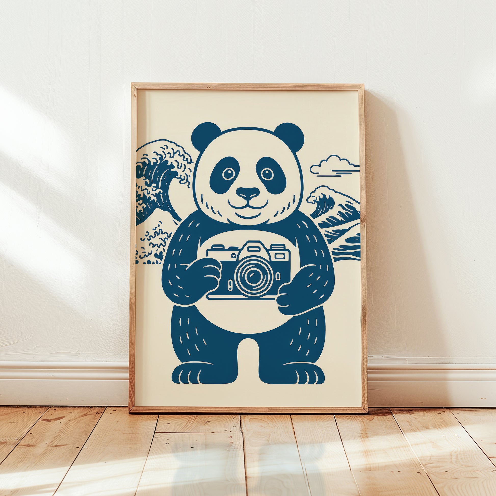 Framed panda photographer art print in wooden frame, navy blue line illustration with smiling panda holding vintage camera and Hokusai Great Wave background on cream