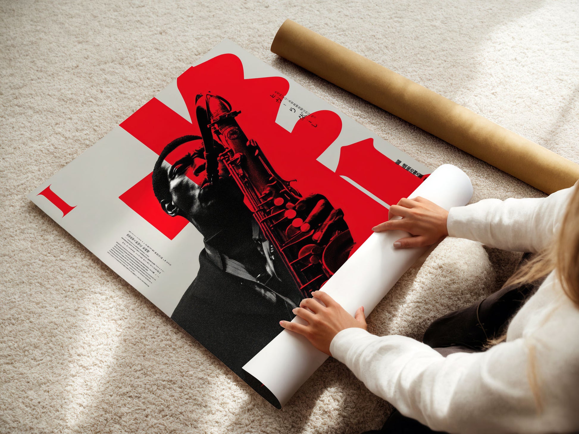 Person unrolling a large poster with a red and black design on a light-colored floor.