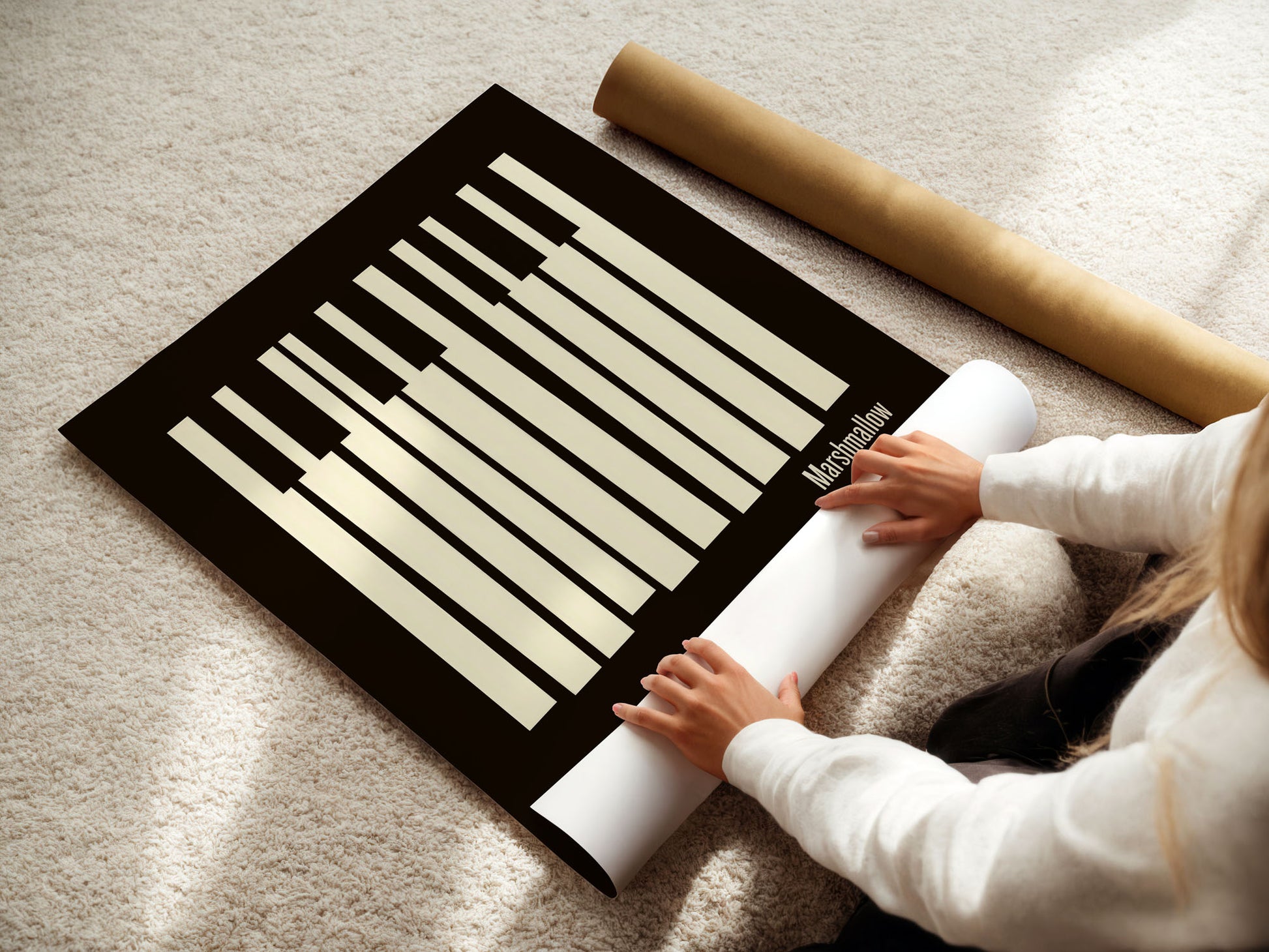 Person unrolling a large poster of a keyboard layout on a carpeted floor.