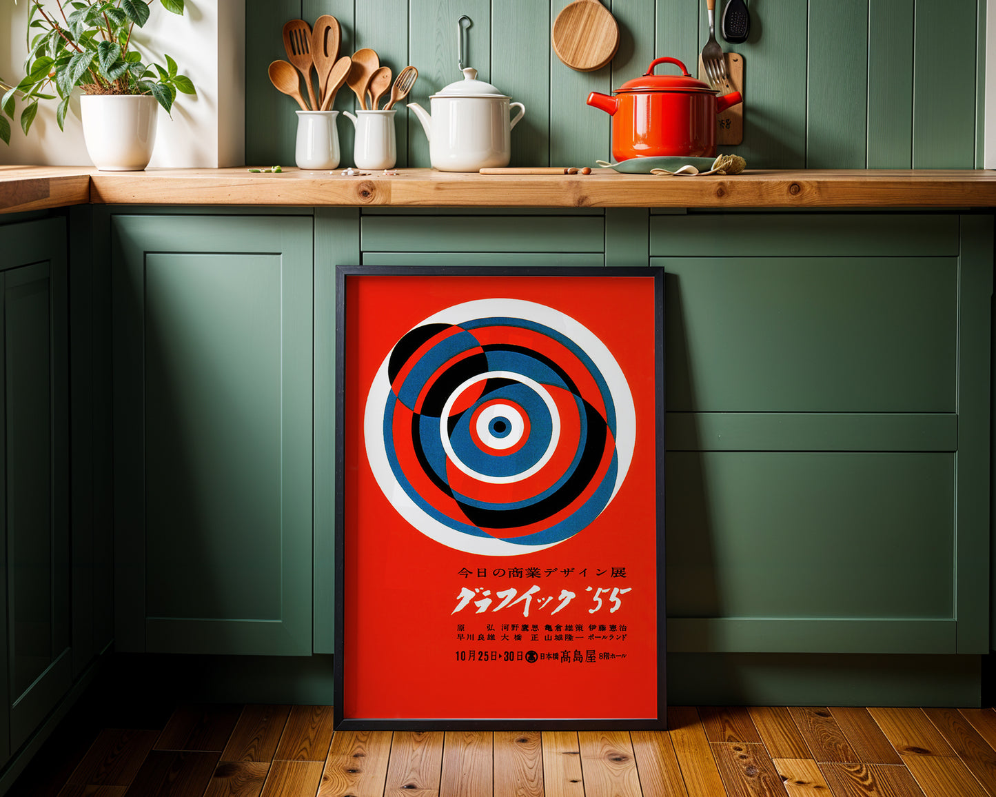 Framed abstract art on a kitchen wall with green cabinets and wooden countertop.
