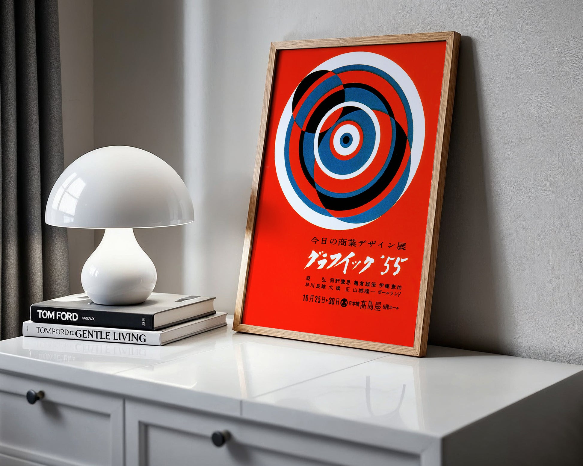 Framed abstract art on a shelf with a white lamp and books