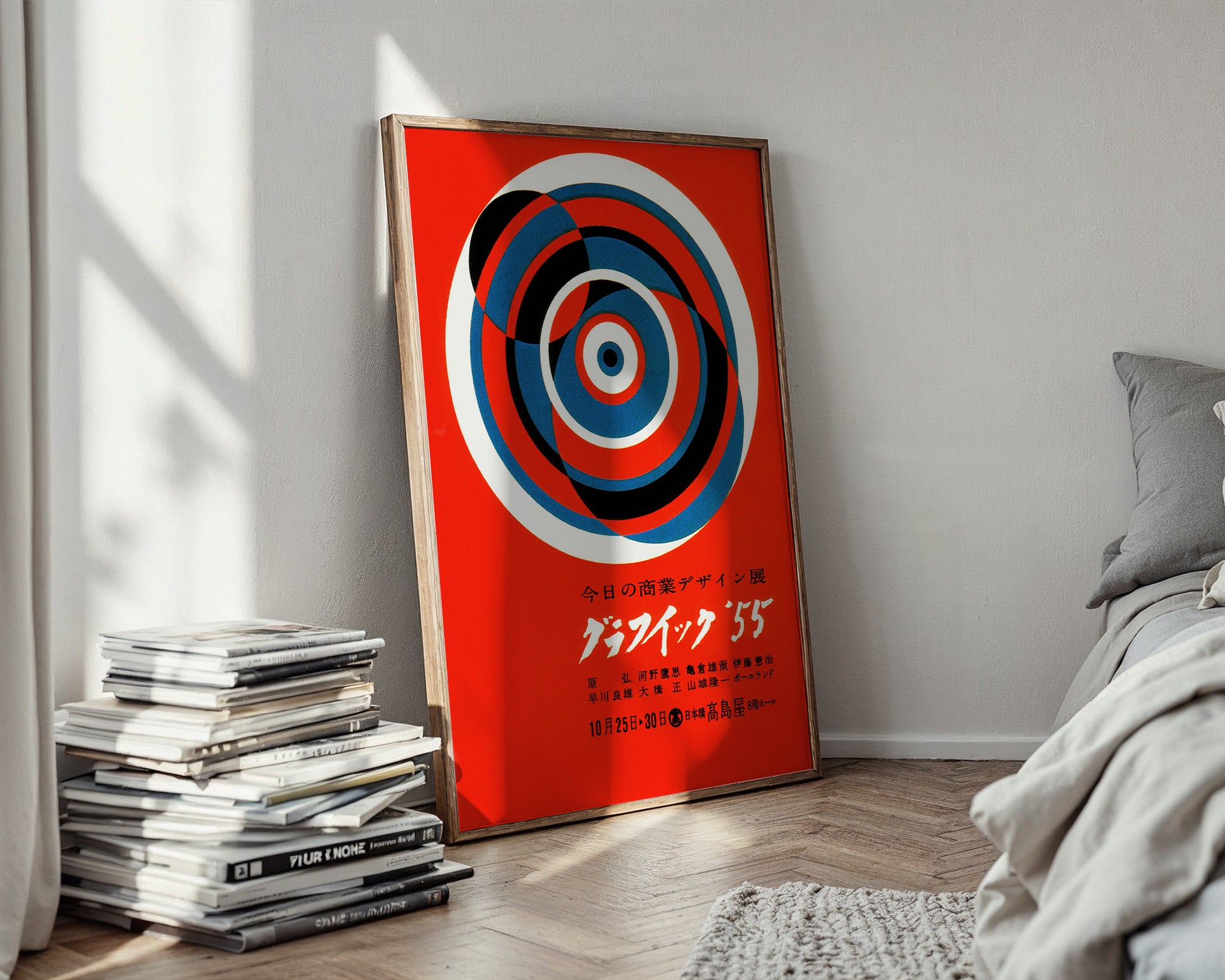 Decorative poster with concentric circles on a red background in a room with books and a bed.