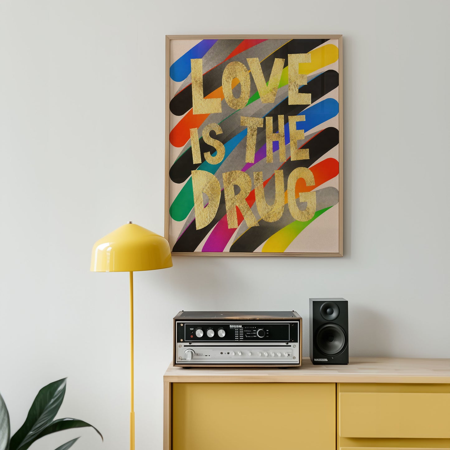 Colorful 'LOVE IS THE DRUG' poster above a yellow cabinet with audio equipment.