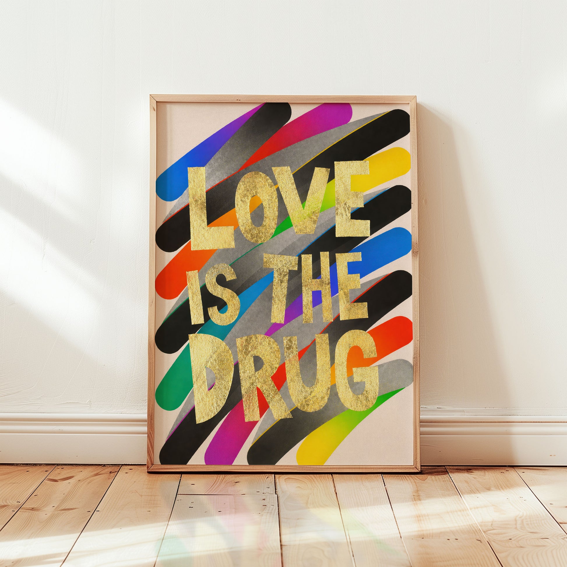 Framed artwork with colorful design and 'LOVE IS THE DRUG' text on a white wall.