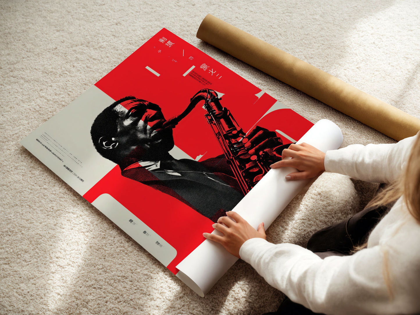 Person unrolling a large poster of a black figure with a red background on a light-colored floor.