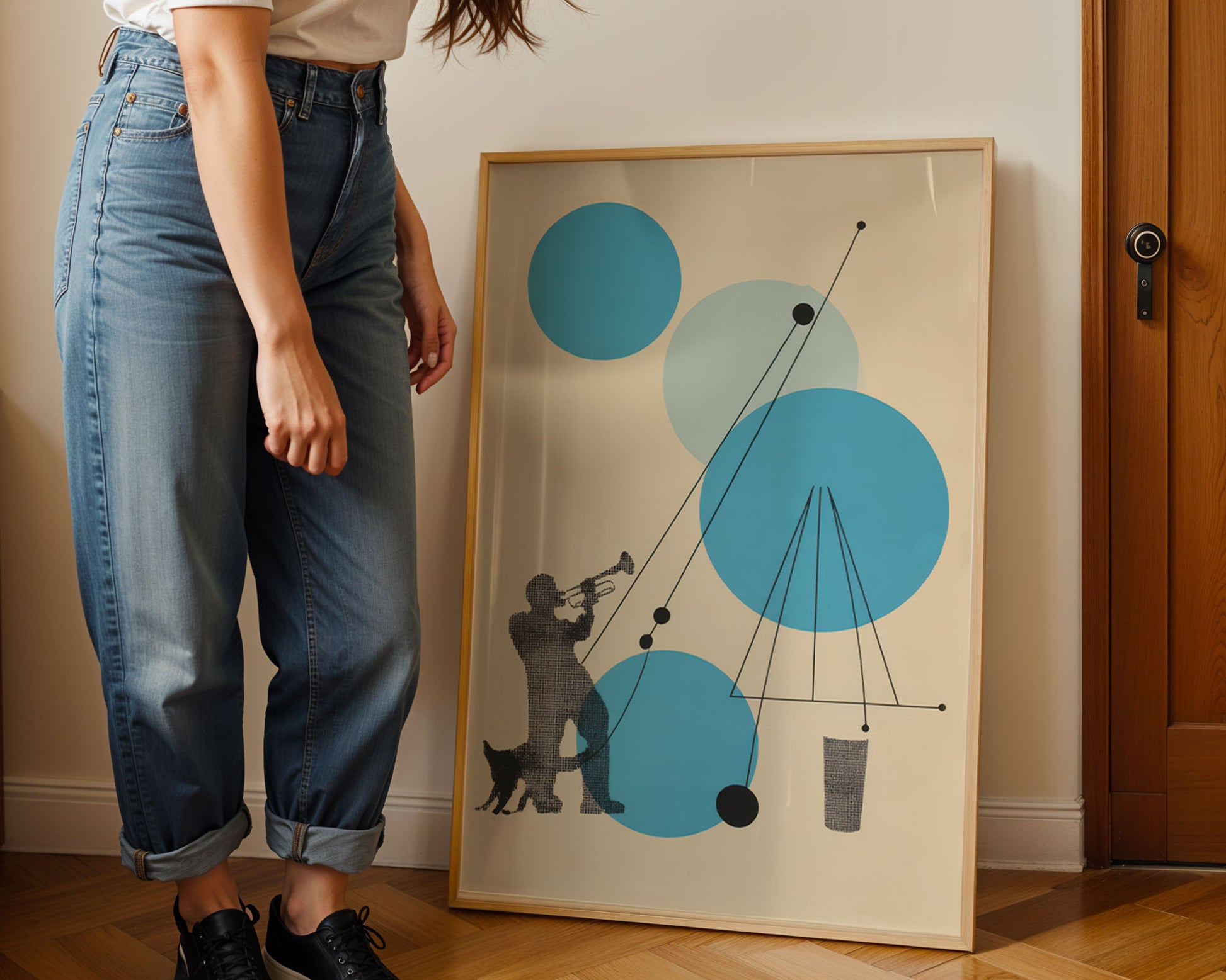 Person standing next to a framed abstract artwork with blue and gray circles on a beige wall.