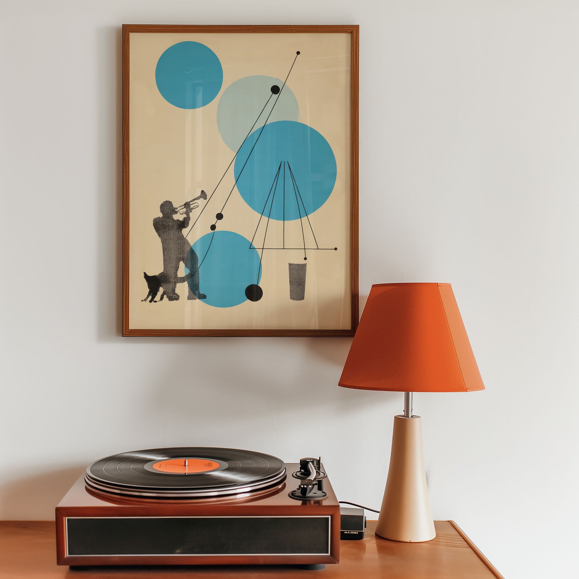 Vintage-style record player with a framed abstract art piece and orange lamp on a wooden surface.