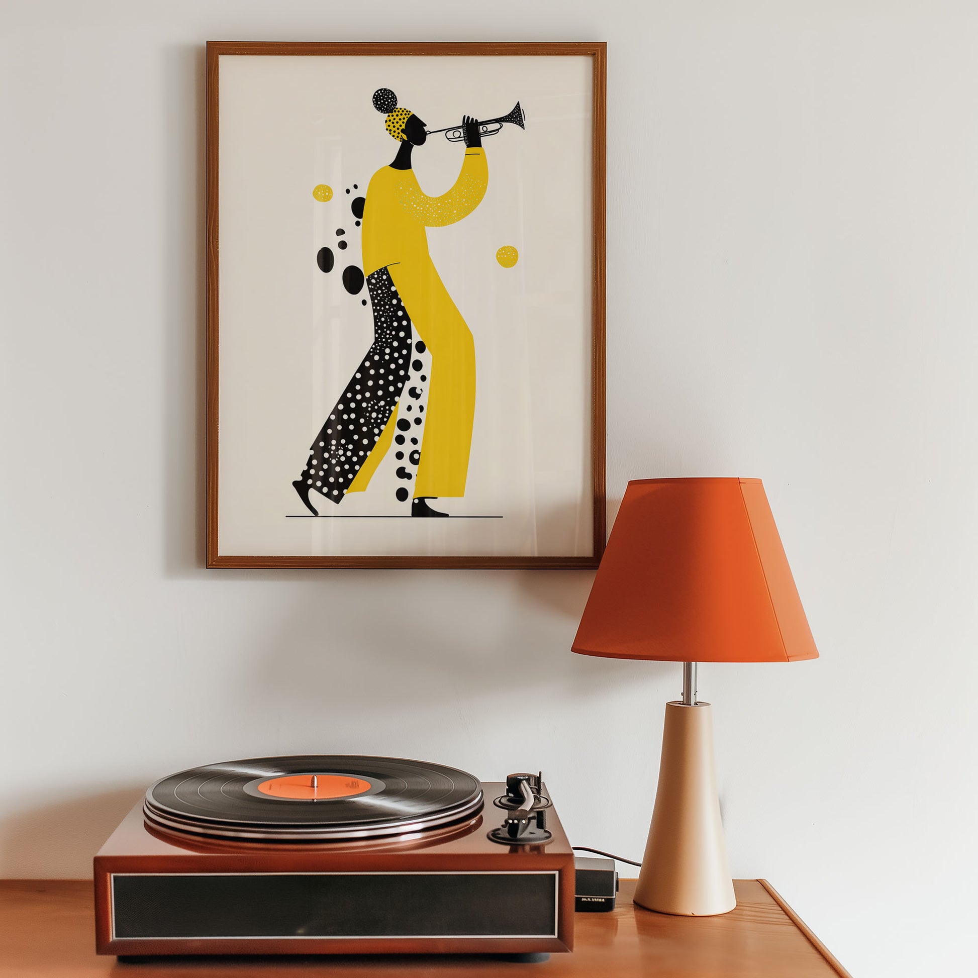 Framed artwork of a person playing a trumpet above a record player with an orange lamp.