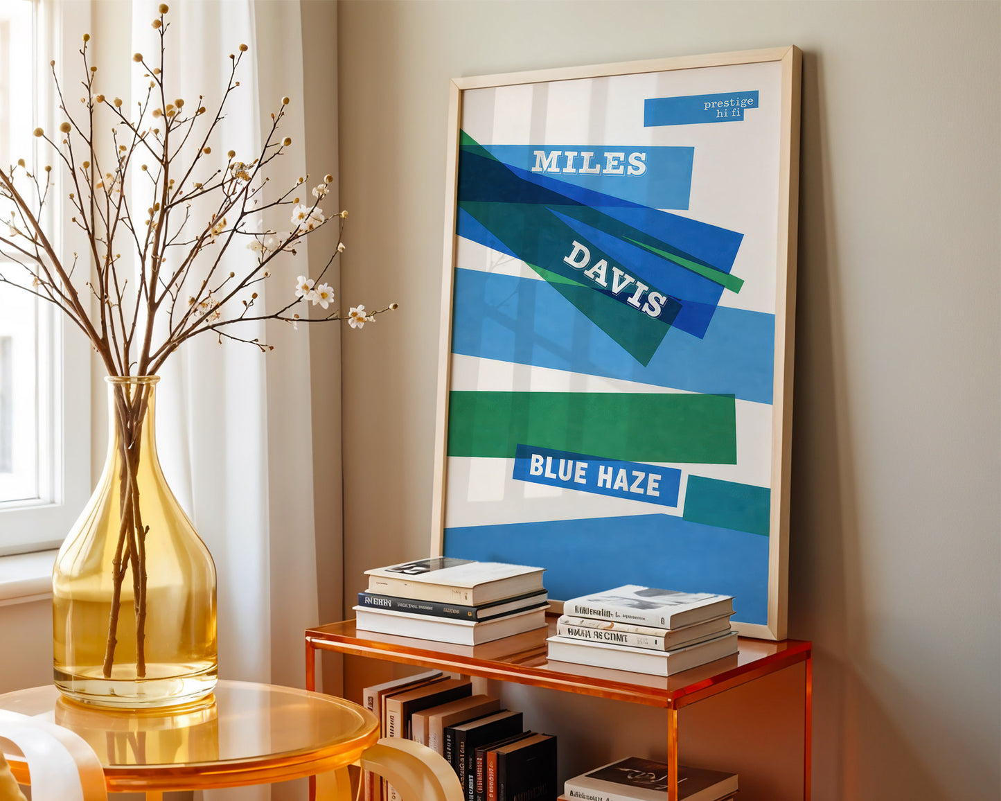 Framed Miles Davis 'Blue Haze' poster on a shelf with books and a vase.