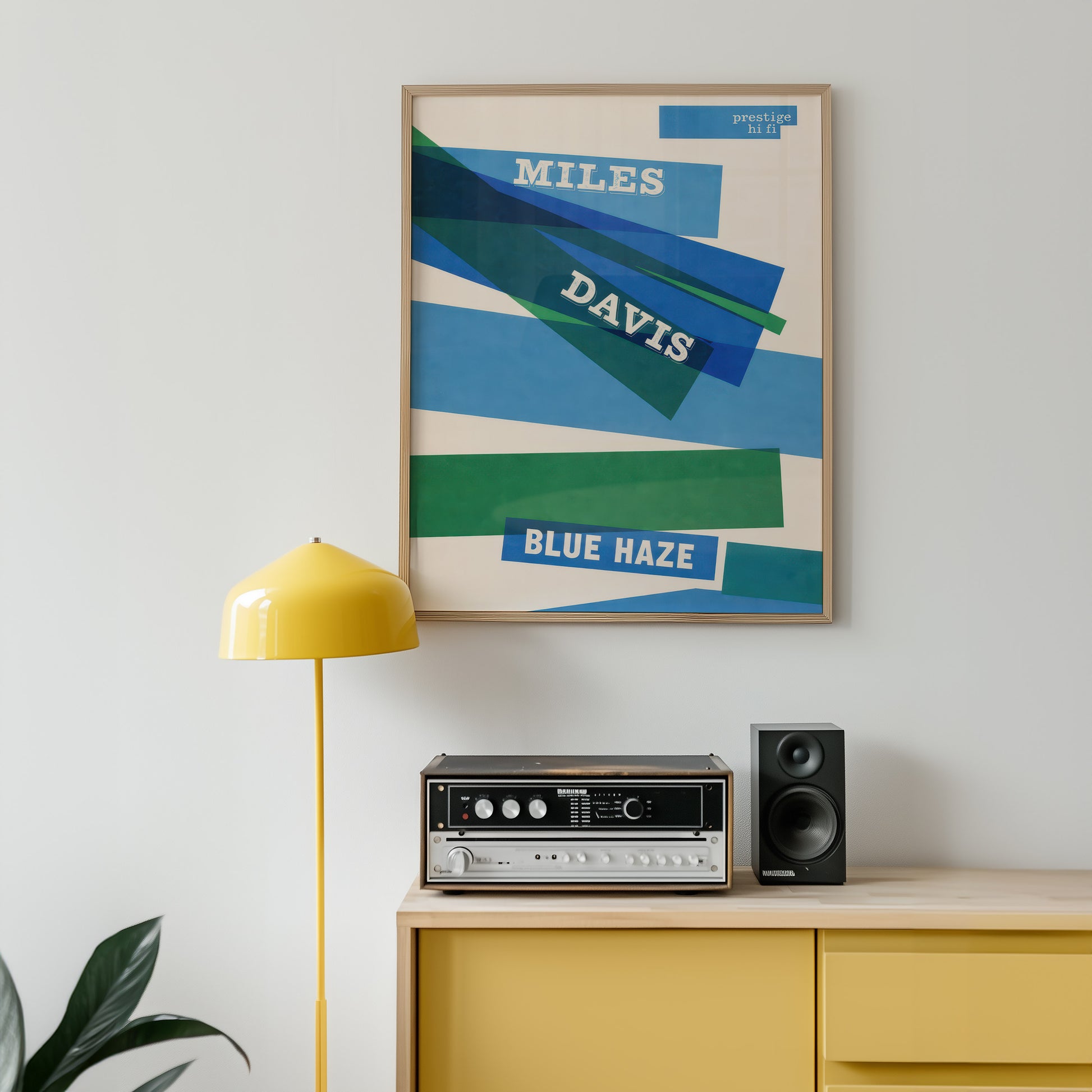 Framed Miles Davis 'Blue Haze' poster above a yellow cabinet with stereo equipment.