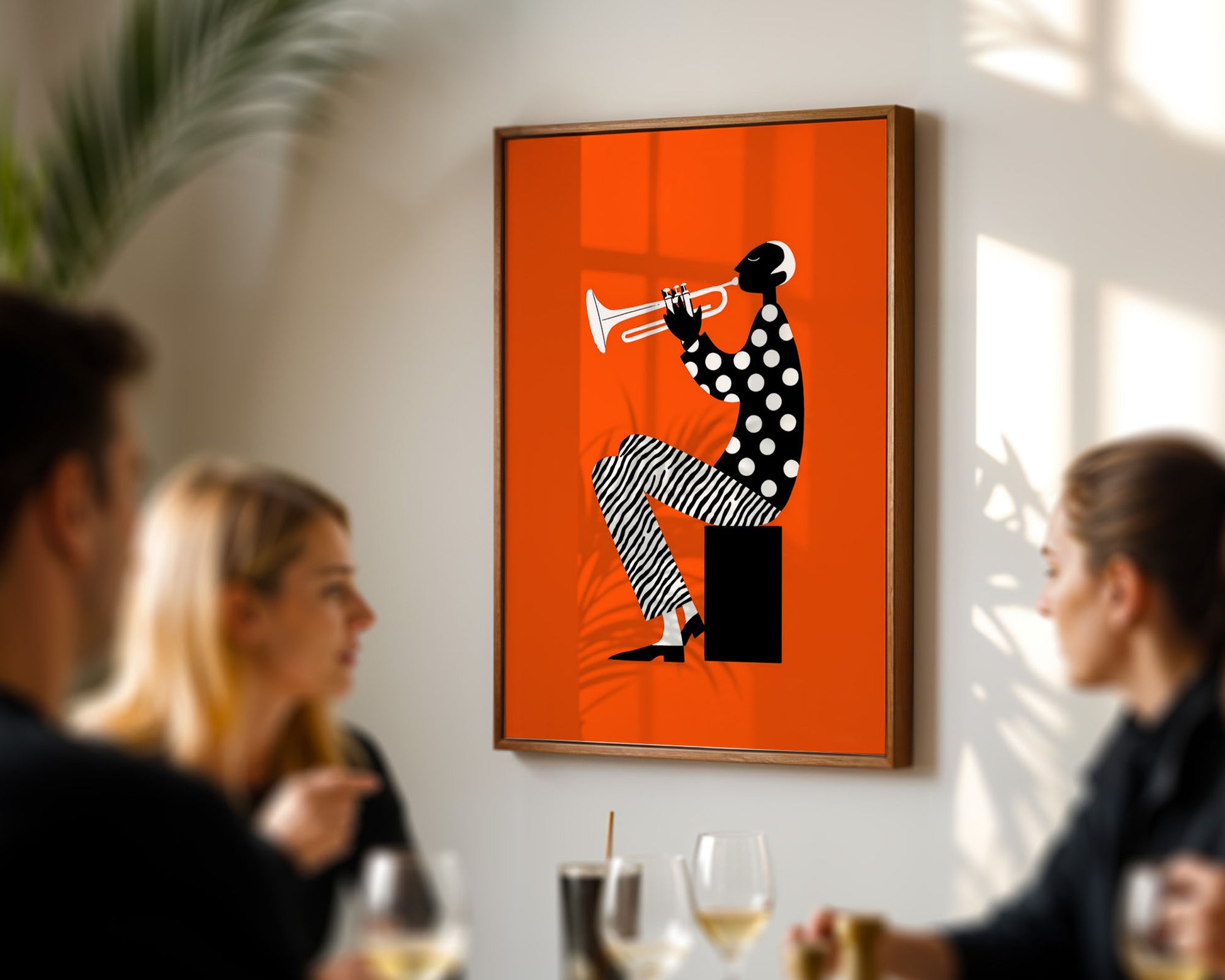 Framed artwork of a polka-dotted figure playing a trumpet on an orange background, hanging in a room with people socializing.