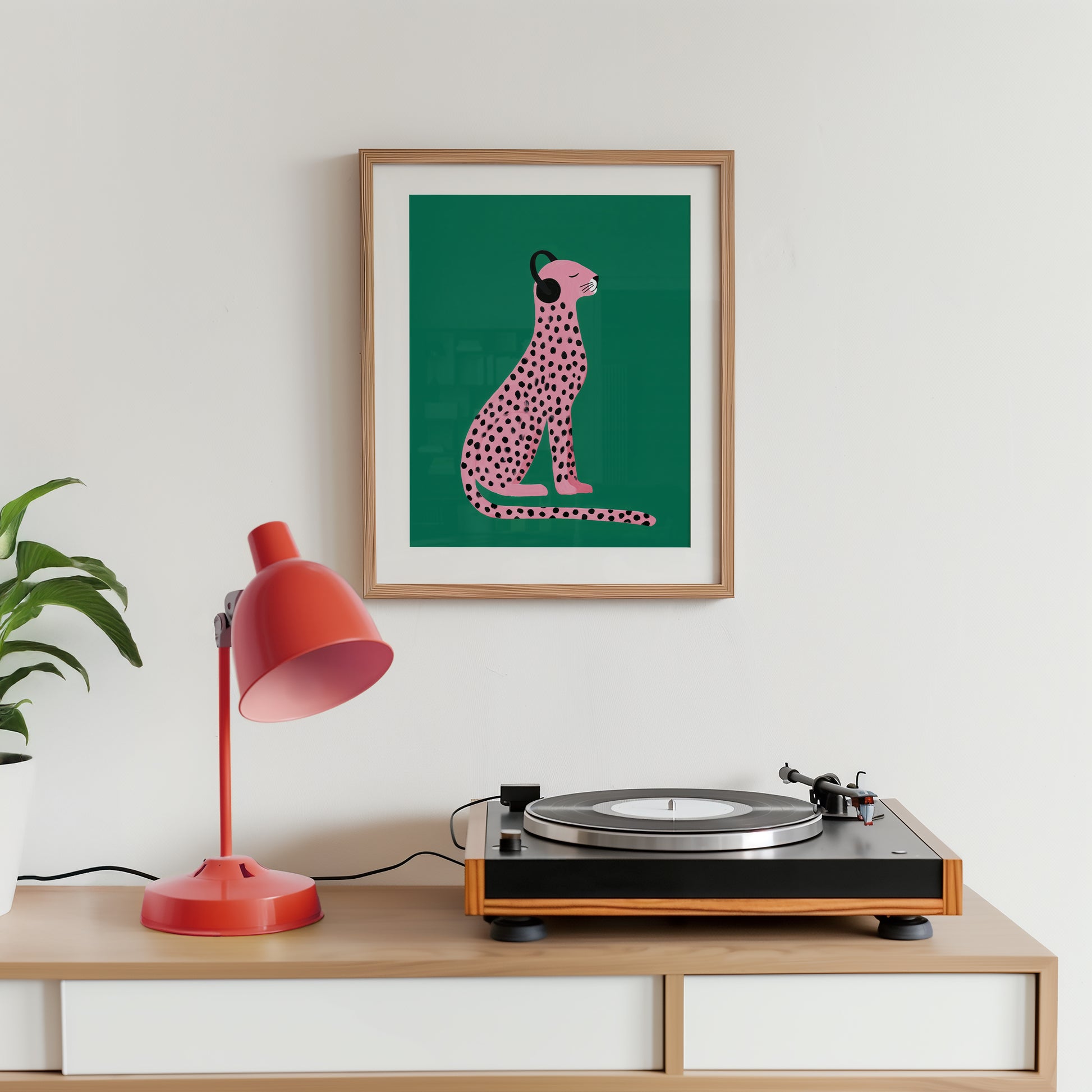 Framed artwork of a pink cheetah with headphones on a turntable and red lamp.