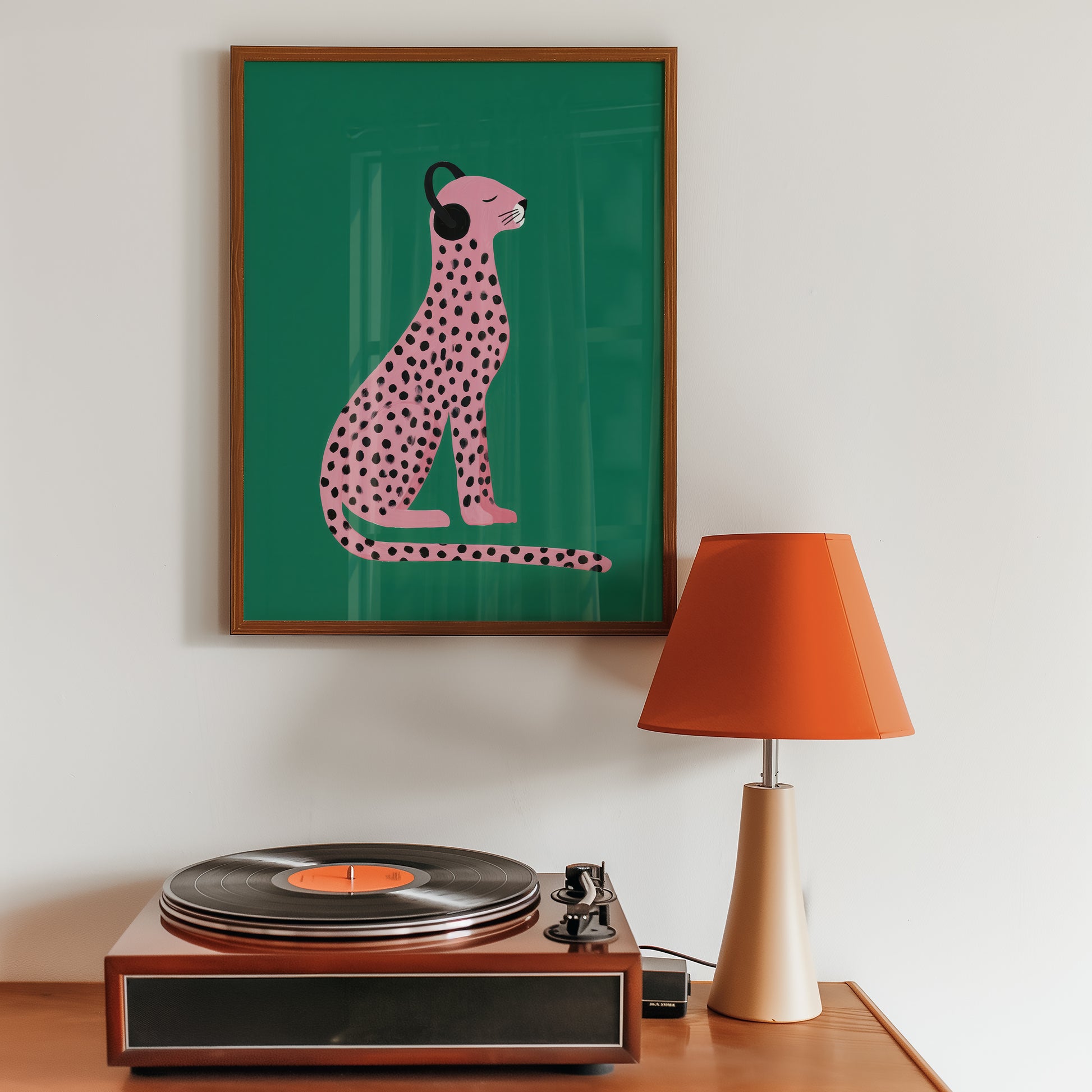 eclectic home decor artwork of a pink cheetah on a green background above a record player with an orange lamp.