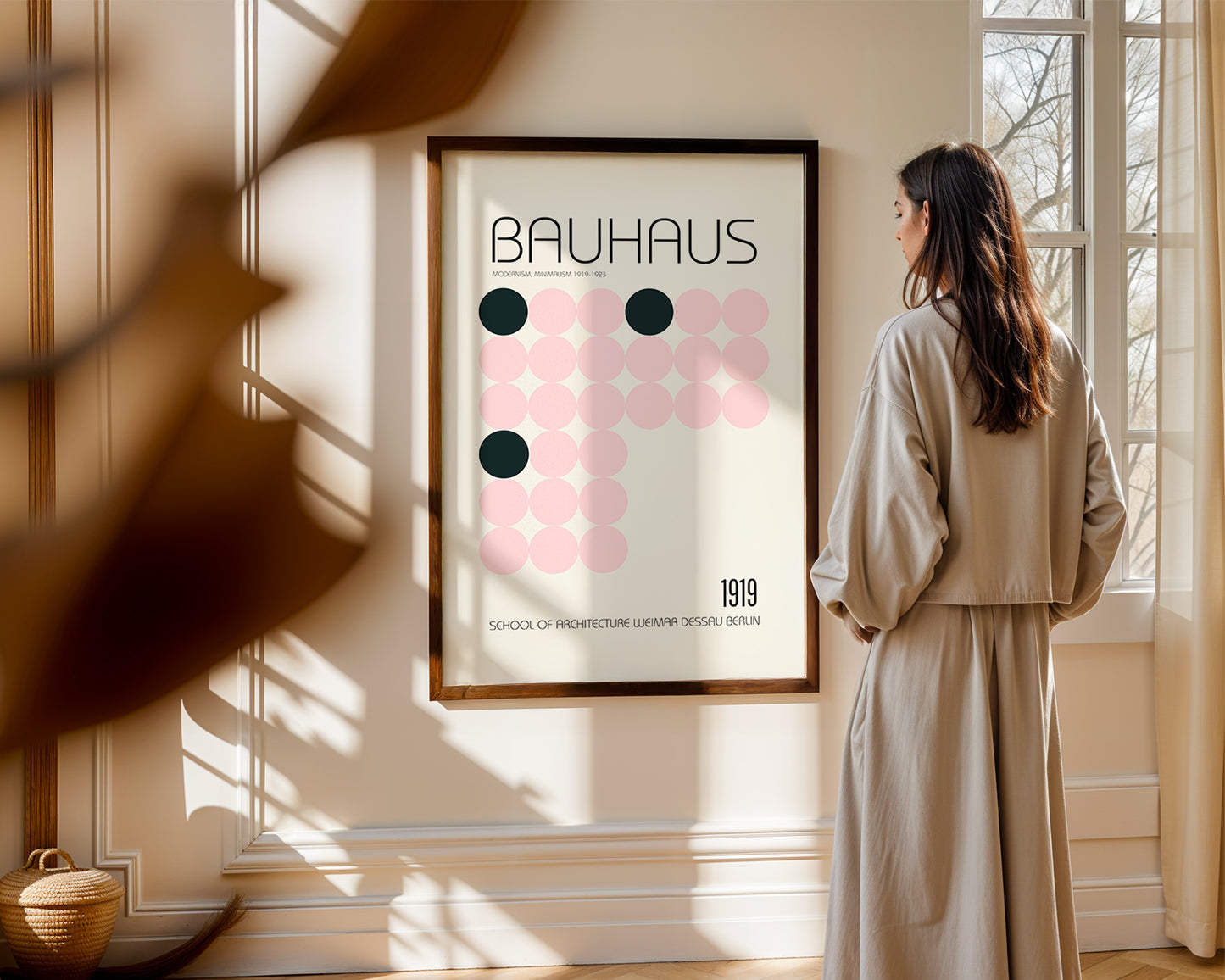 Woman standing in a room looking at a Bauhaus poster on the wall.