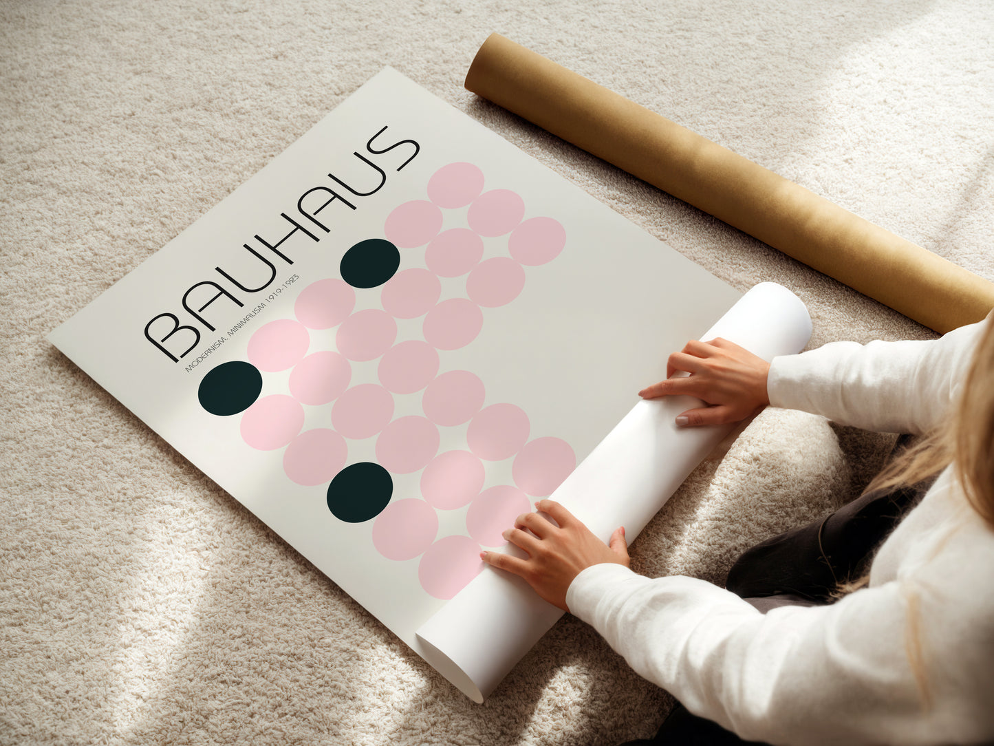 Person unrolling a poster with 'Bauhaus' design on a light surface