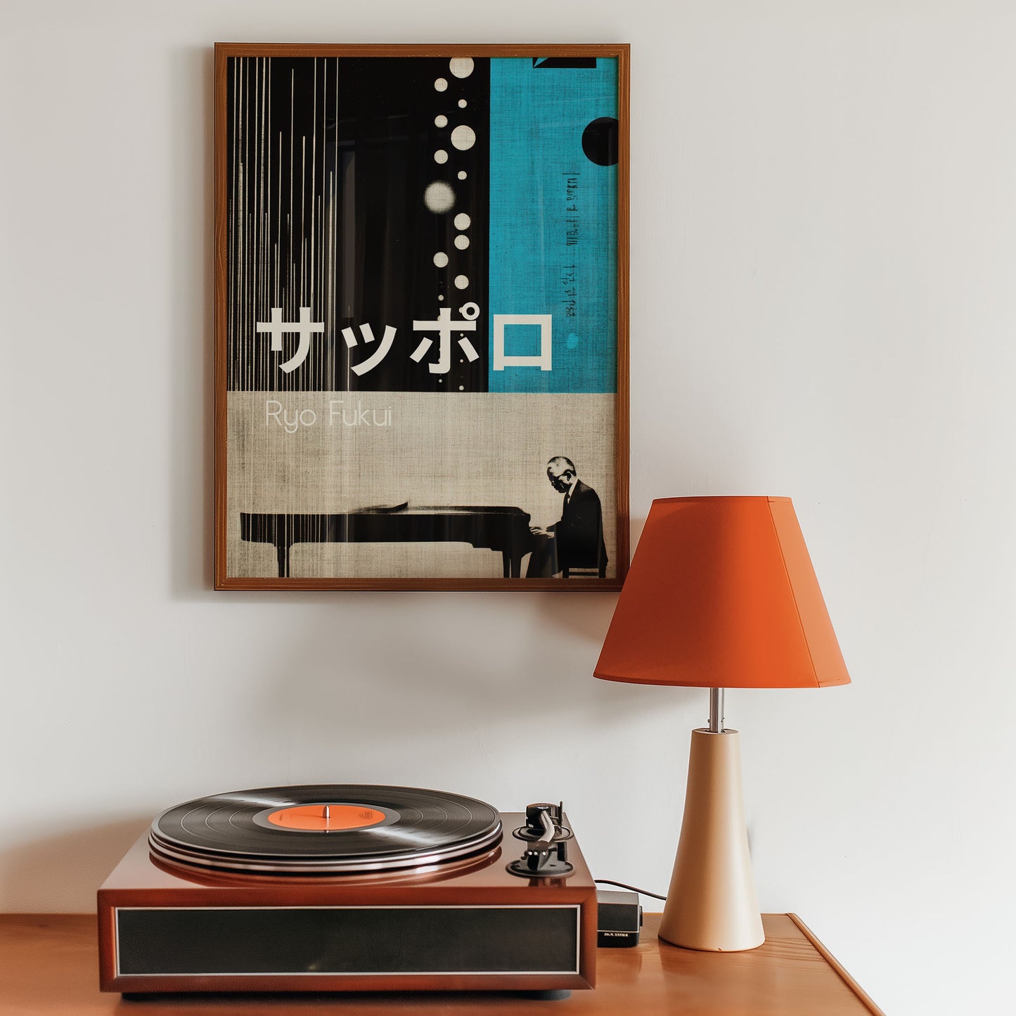 Mid-century inspired art print above a record player with an orange lamp on a wooden surface.