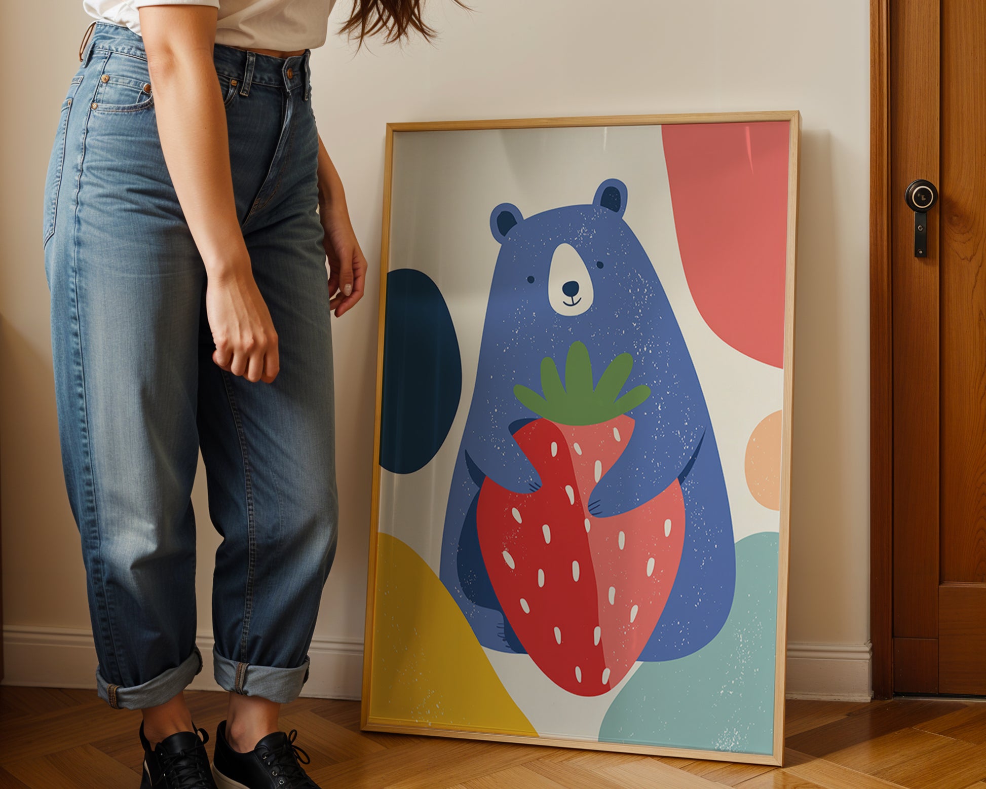 Person standing next to a colorful bear holding a strawberry illustration on a wall.