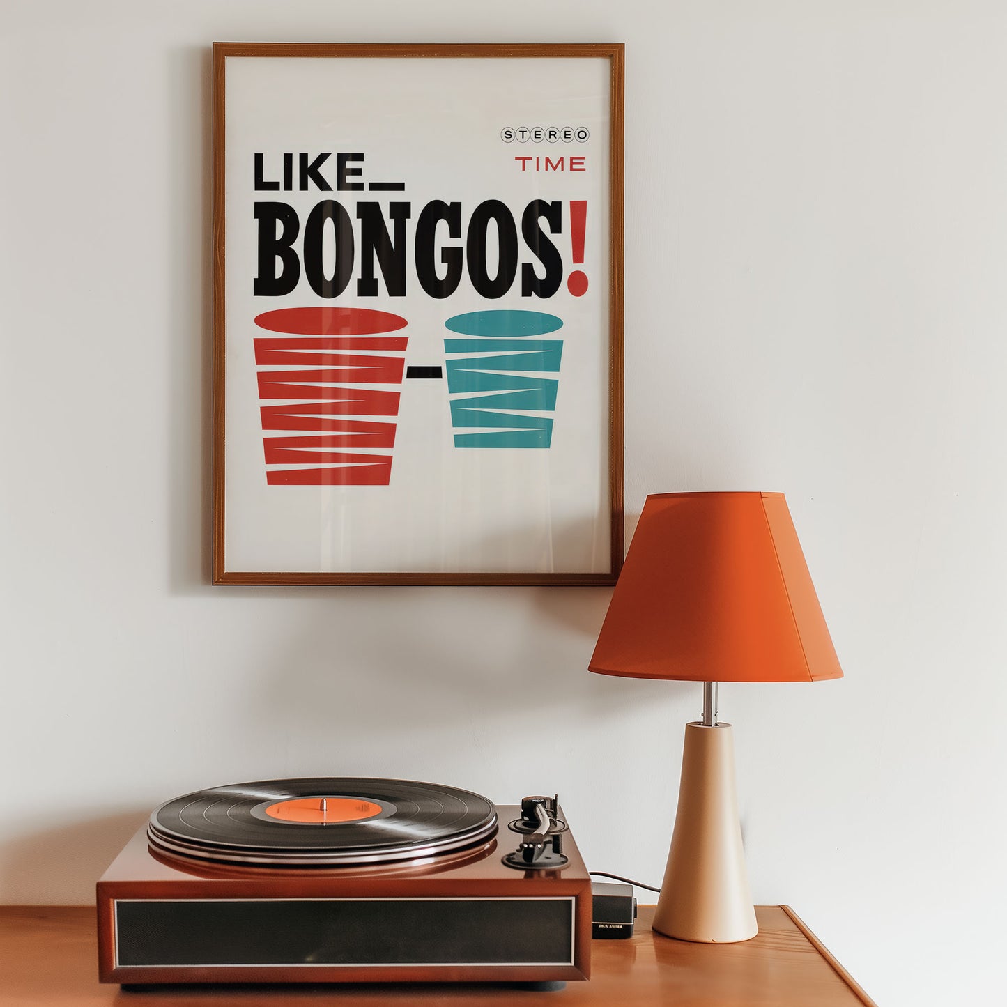 Framed poster with 'Like Bongos!' text above a record player on a wooden surface.
