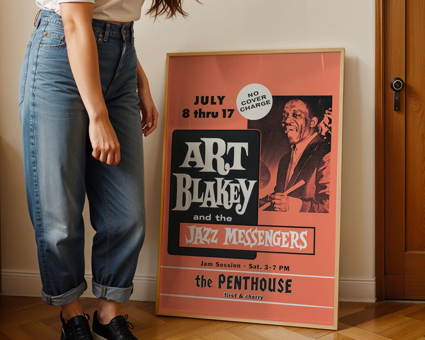 Person standing next to a framed poster of Art Blakey and the Jazz Messengers at the Penthouse.