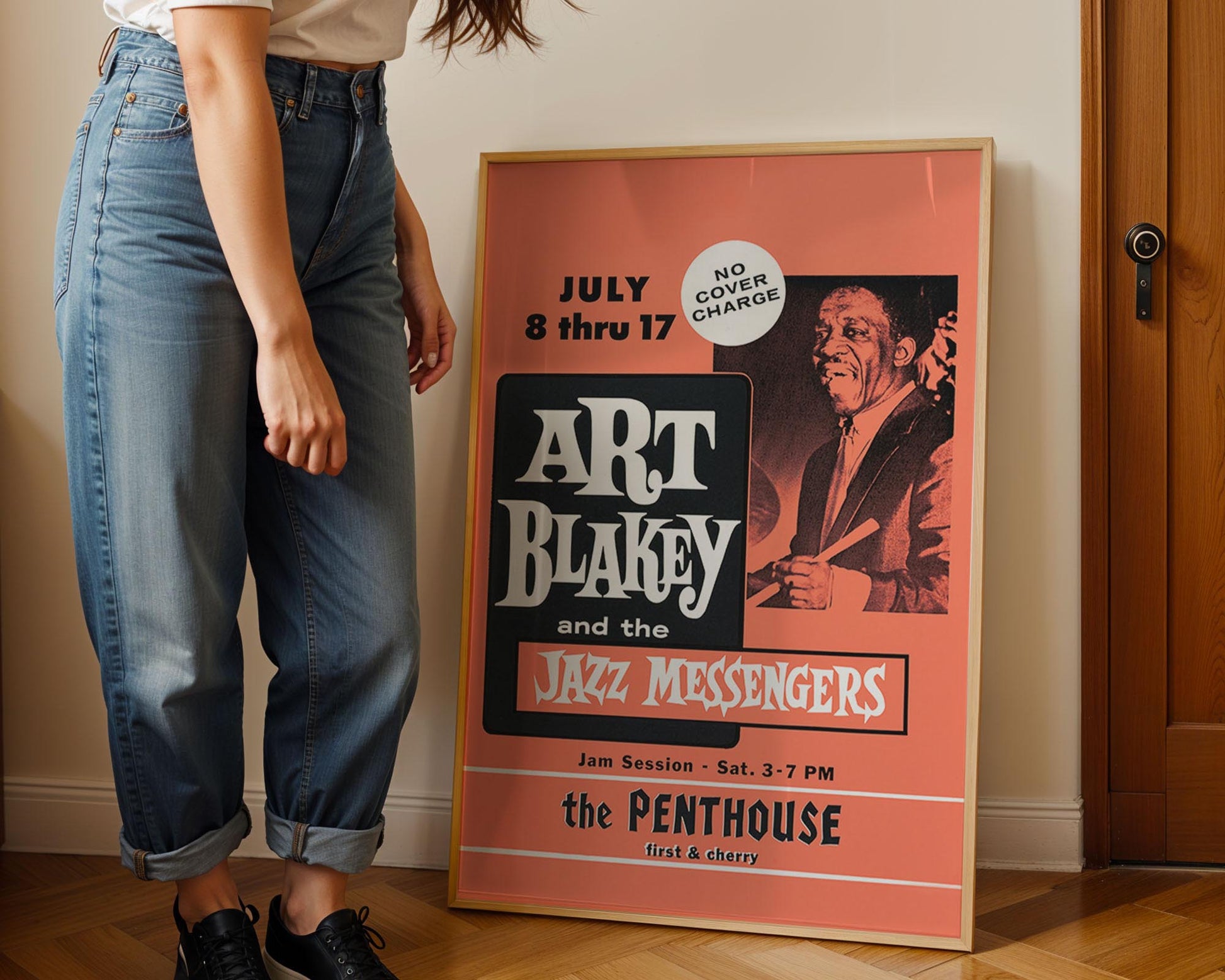Person standing next to a framed poster of Art Blakey and the Jazz Messengers at the Penthouse.