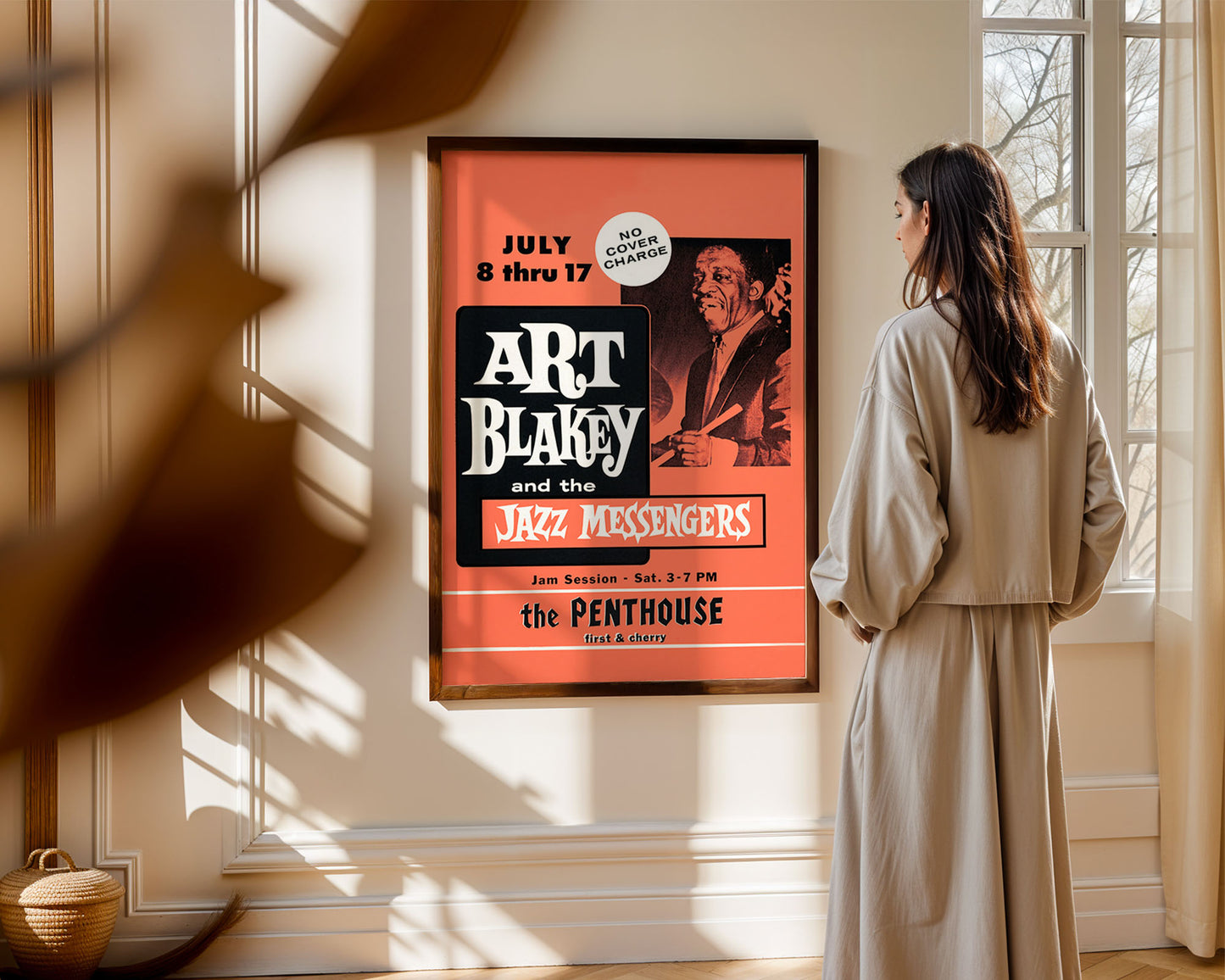 Woman standing in a room looking at a framed jazz poster of Art Blakey and the Jazz Messengers.