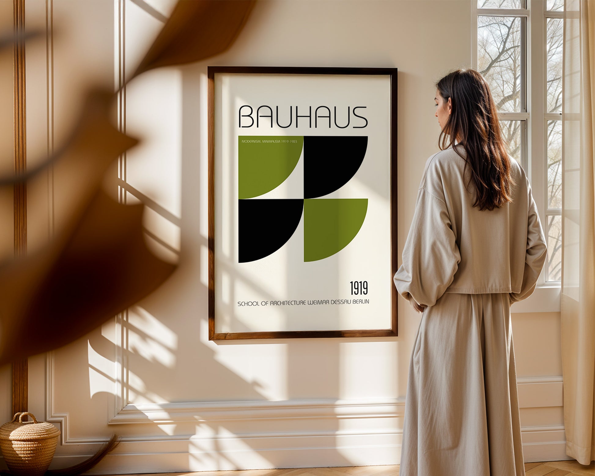 Woman standing in a room looking at a Bauhaus poster on the wall.