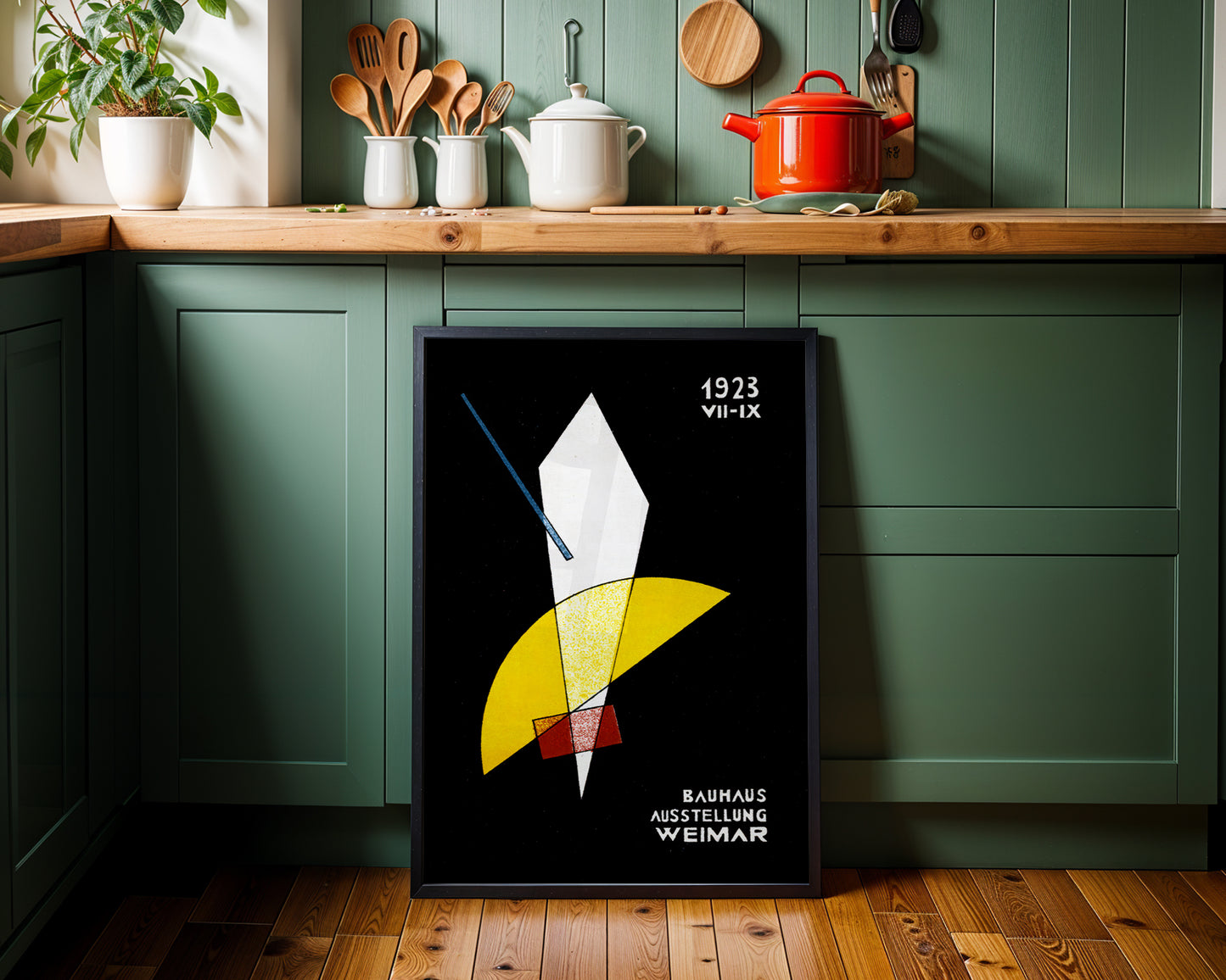 Framed abstract bauhaus- art print on a kitchen wall with green cabinets and wooden countertops.