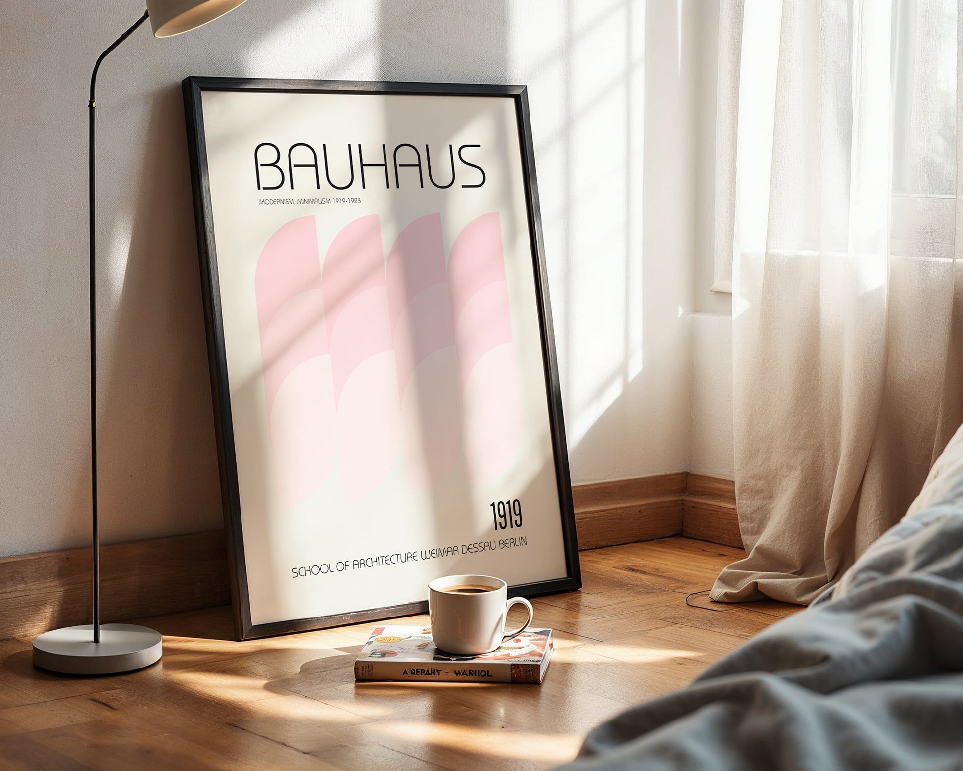 Framed Bauhaus poster on a wall with a cup and book on a surface below.