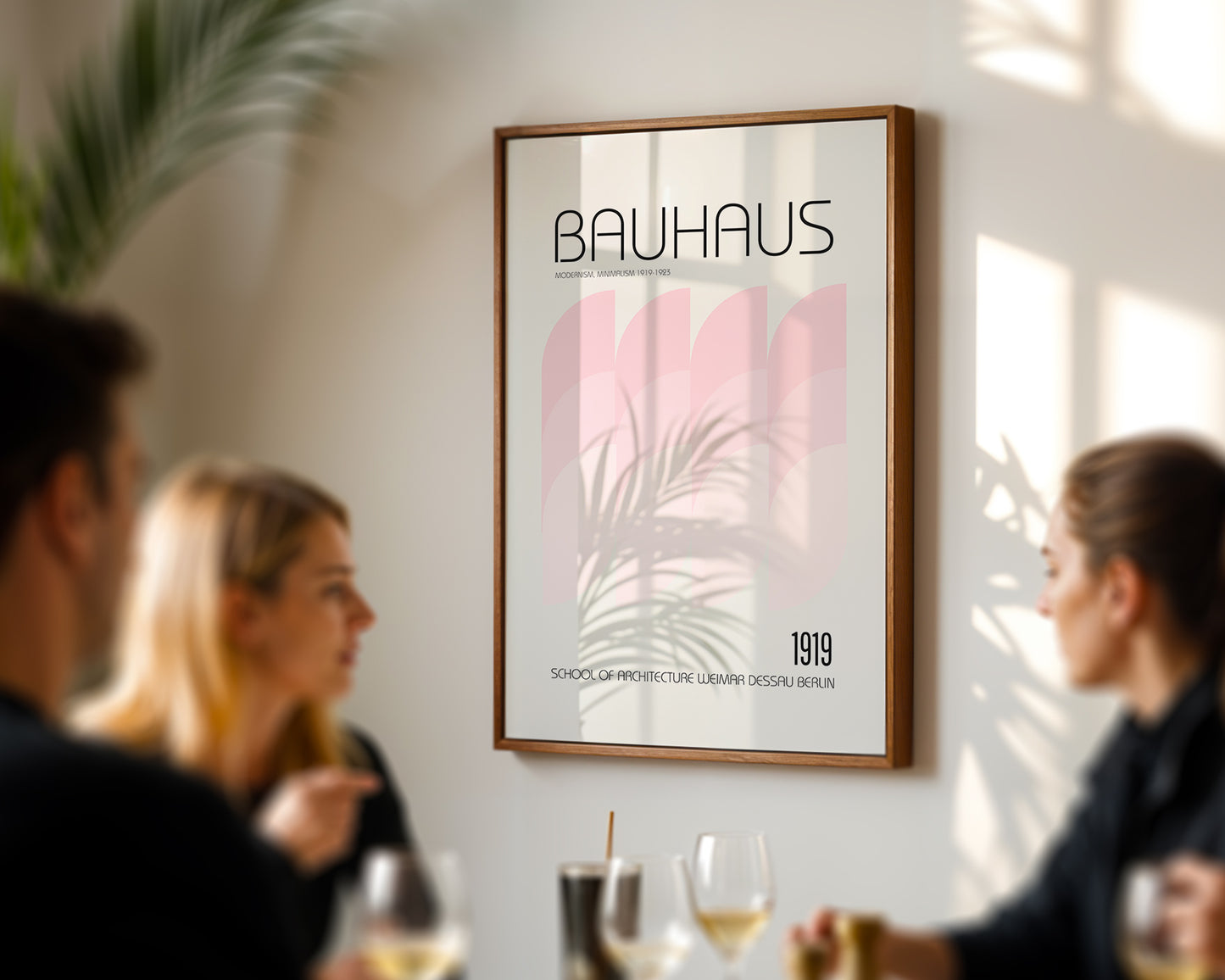Framed Bauhaus poster on a wall with people sitting at a table below.