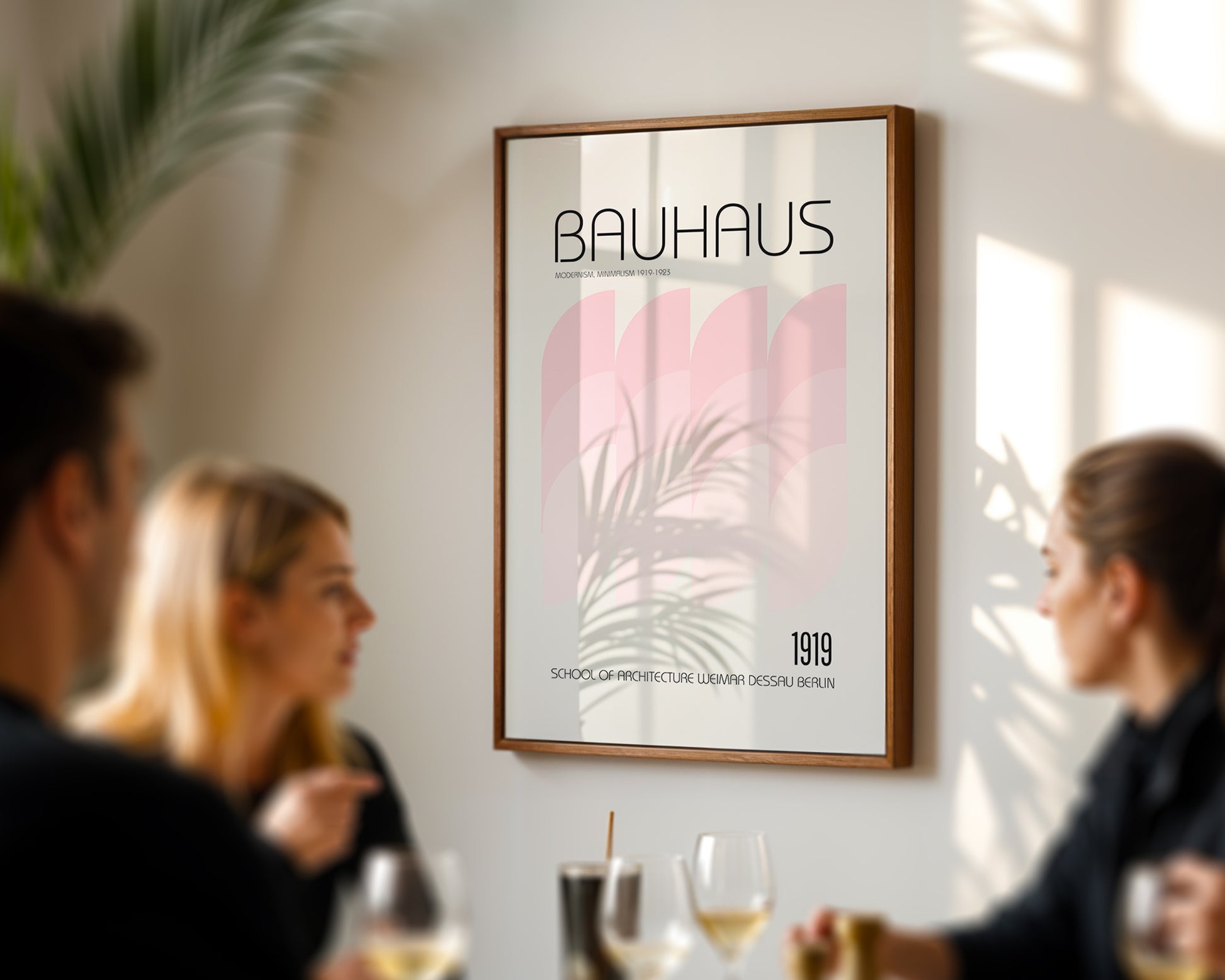 Framed Bauhaus poster on a wall with people sitting at a table below.