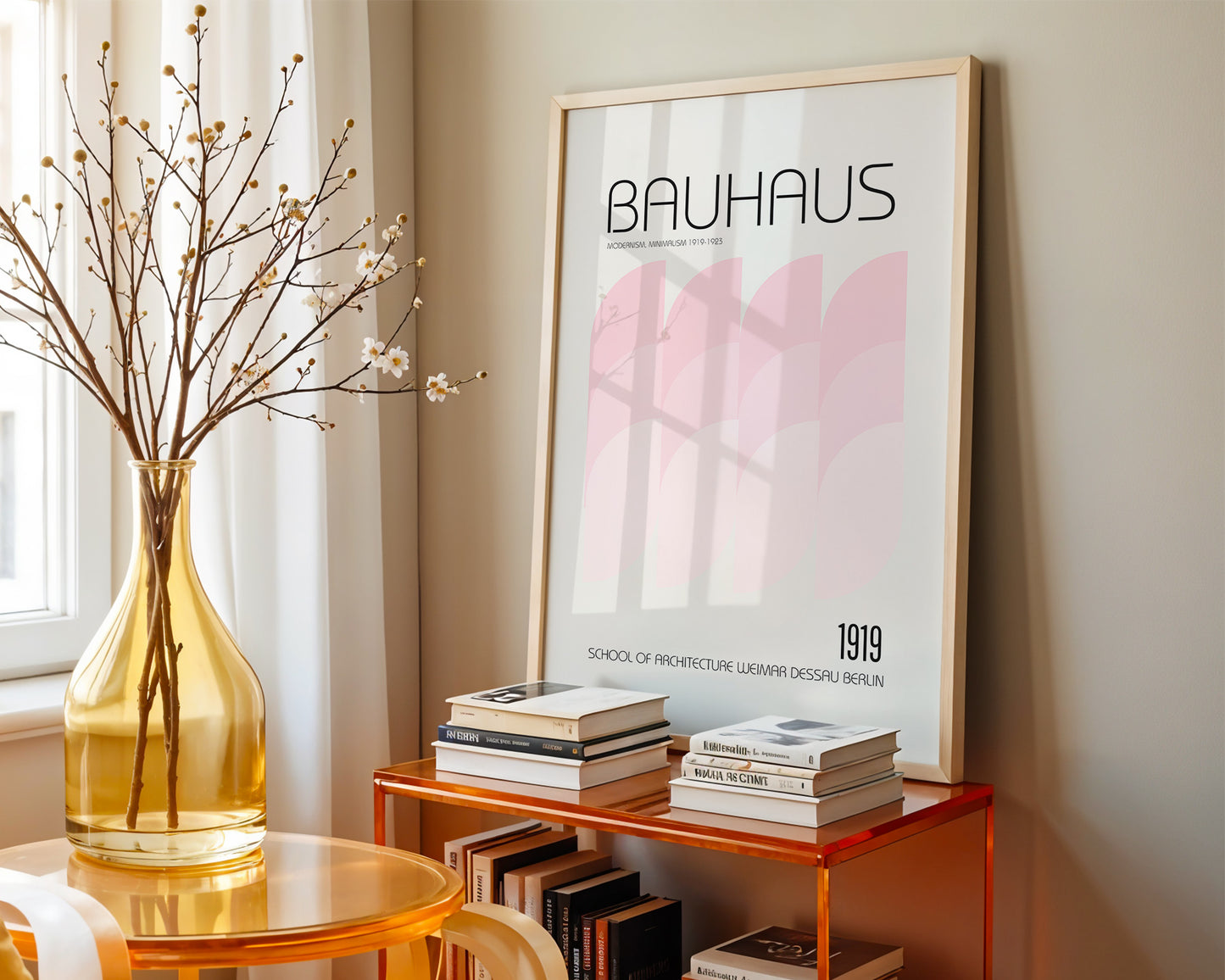 Framed Bauhaus poster on a shelf with books and a vase in a room.