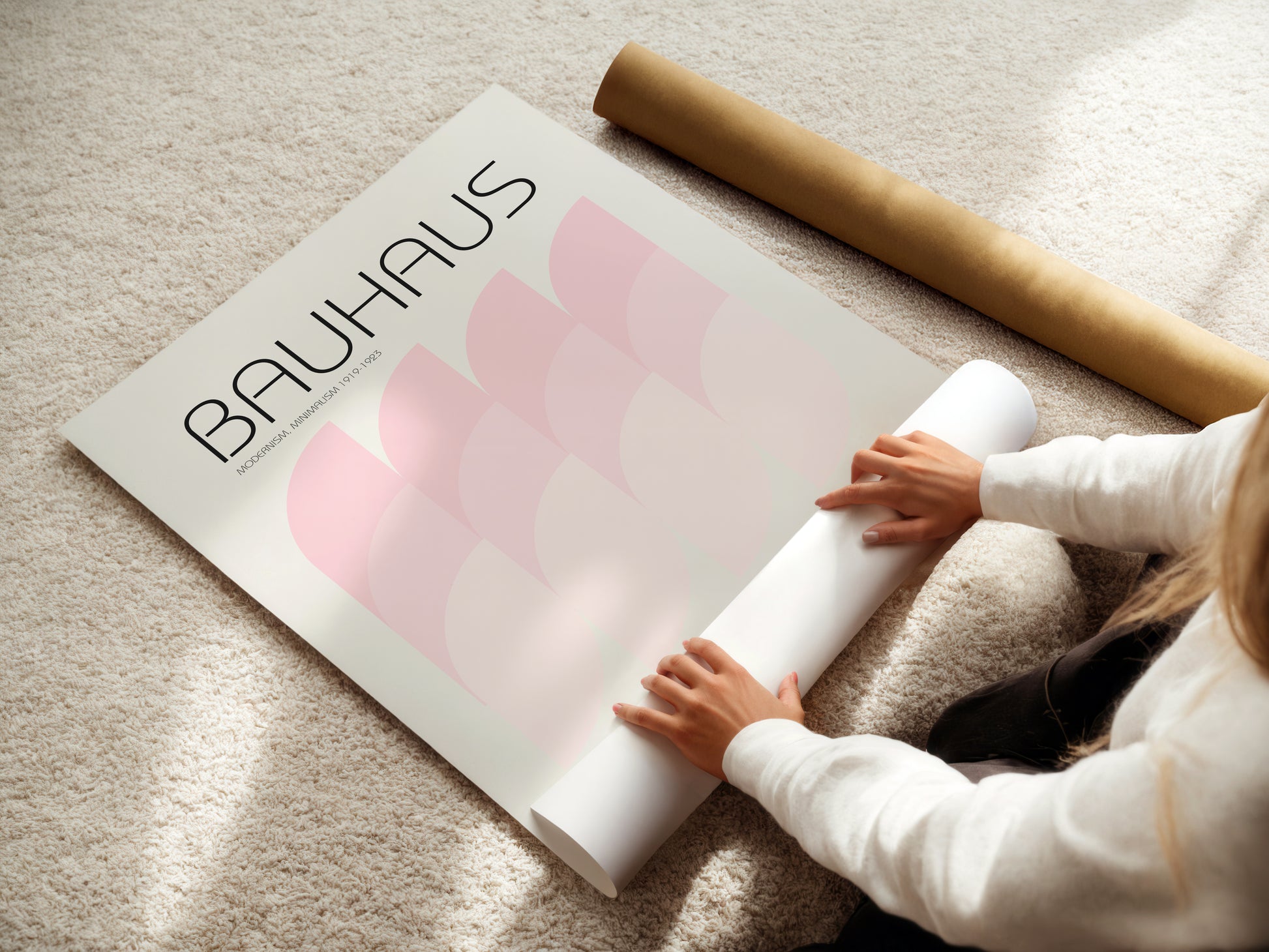 Person unrolling a large poster with 'Bauhaus' branding on a light-colored floor.