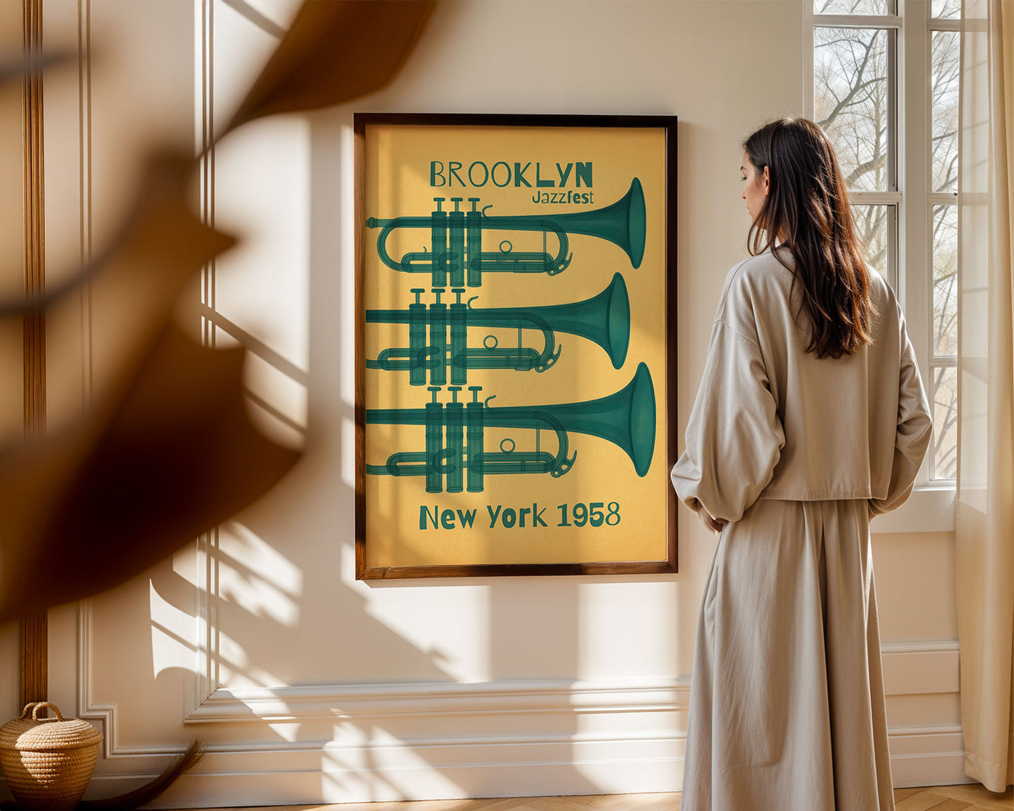 Woman standing in a room looking at a framed poster of trumpets with 'Brooklyn Dazzles New York 1958' text.