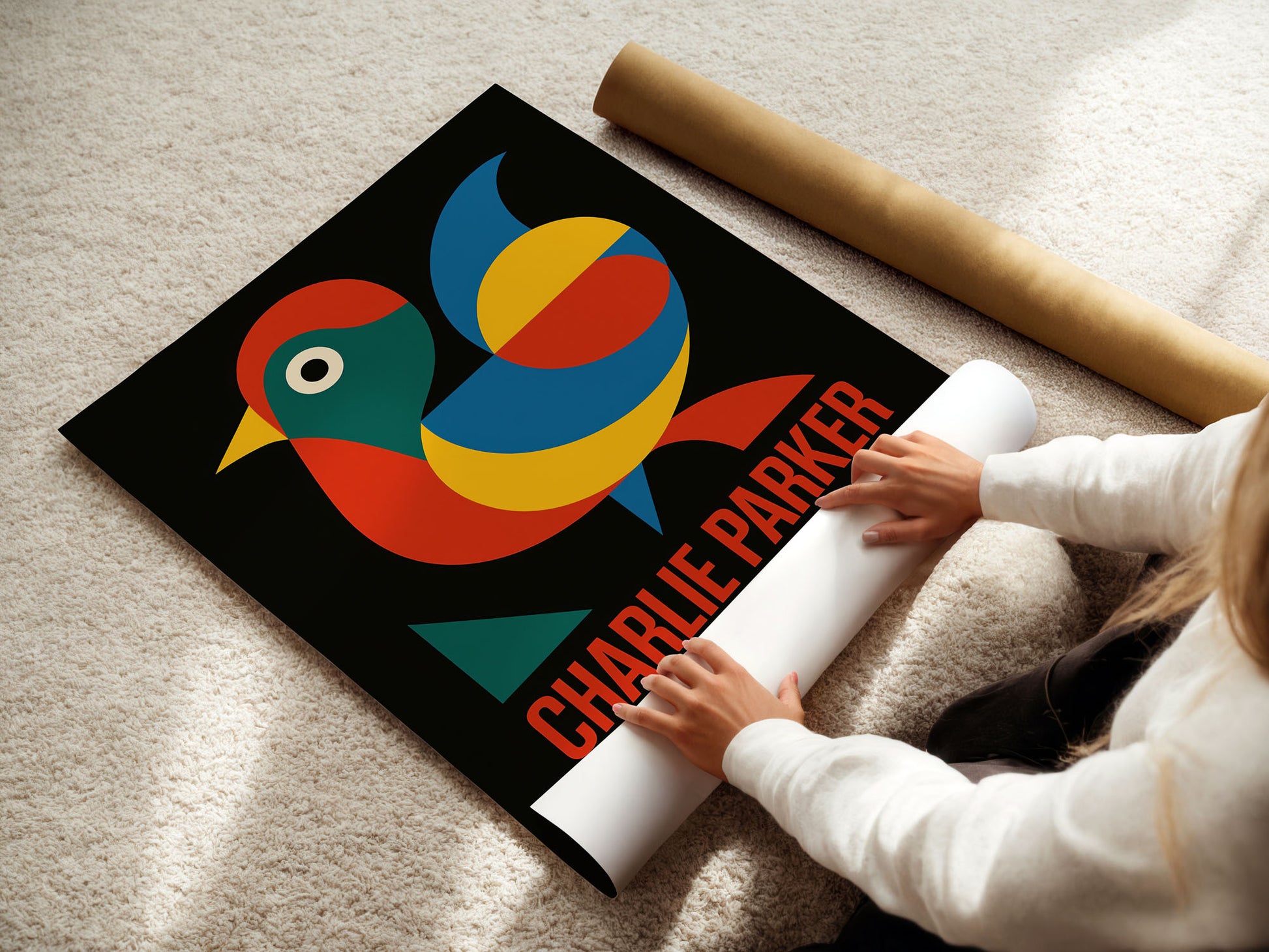 Person unrolling a poster with a colorful bird design and 'Charlie Parker' text on a carpeted floor.