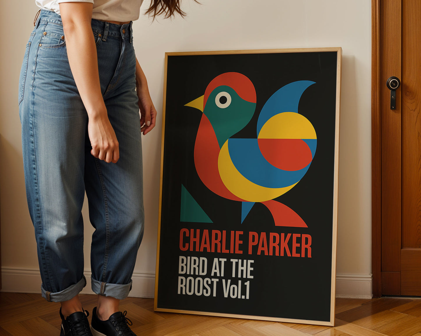 Person standing next to a framed poster of a colorful bird with 'Charlie Parker' text.