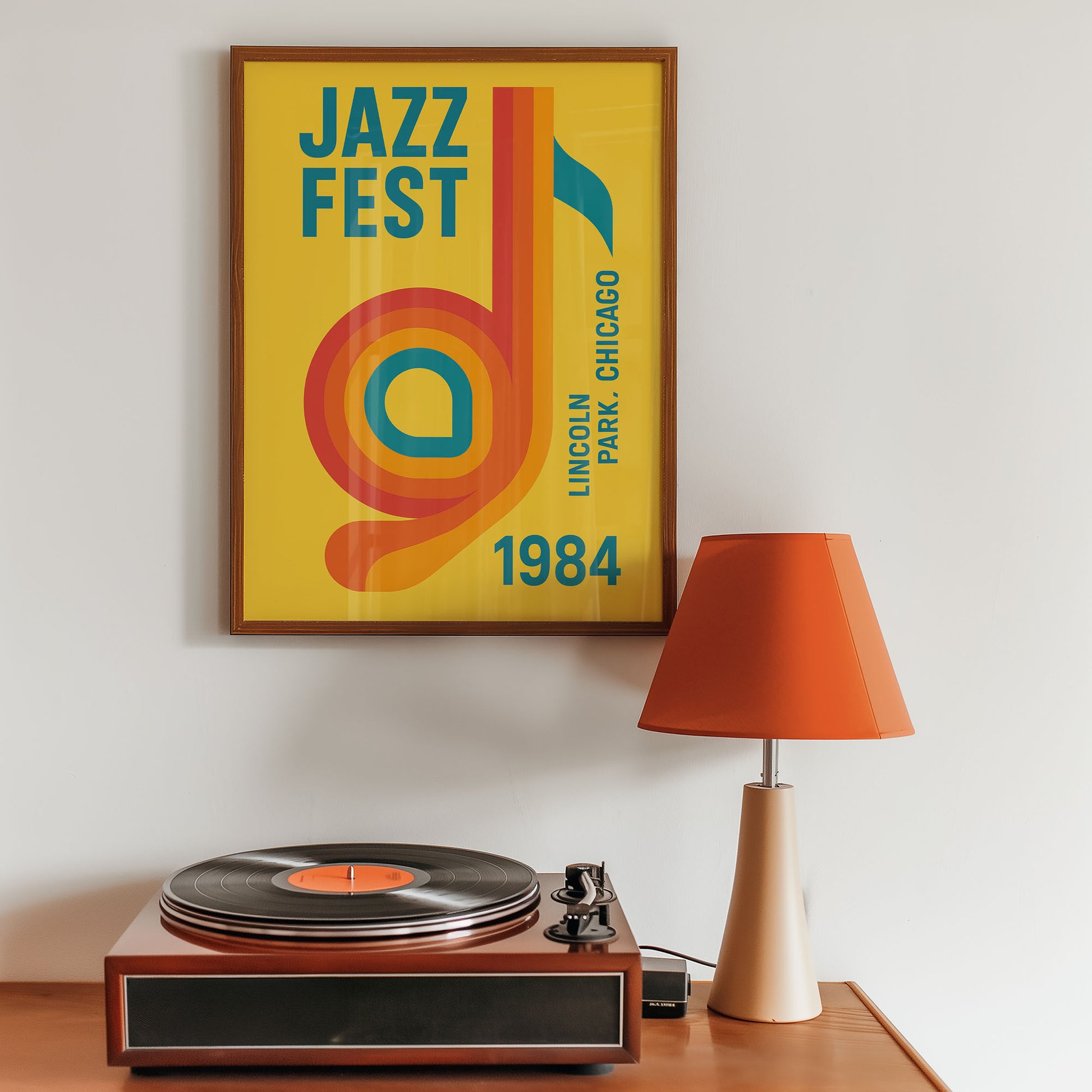 Framed Jazz Fest poster above a record player with an orange lamp on a wooden surface.