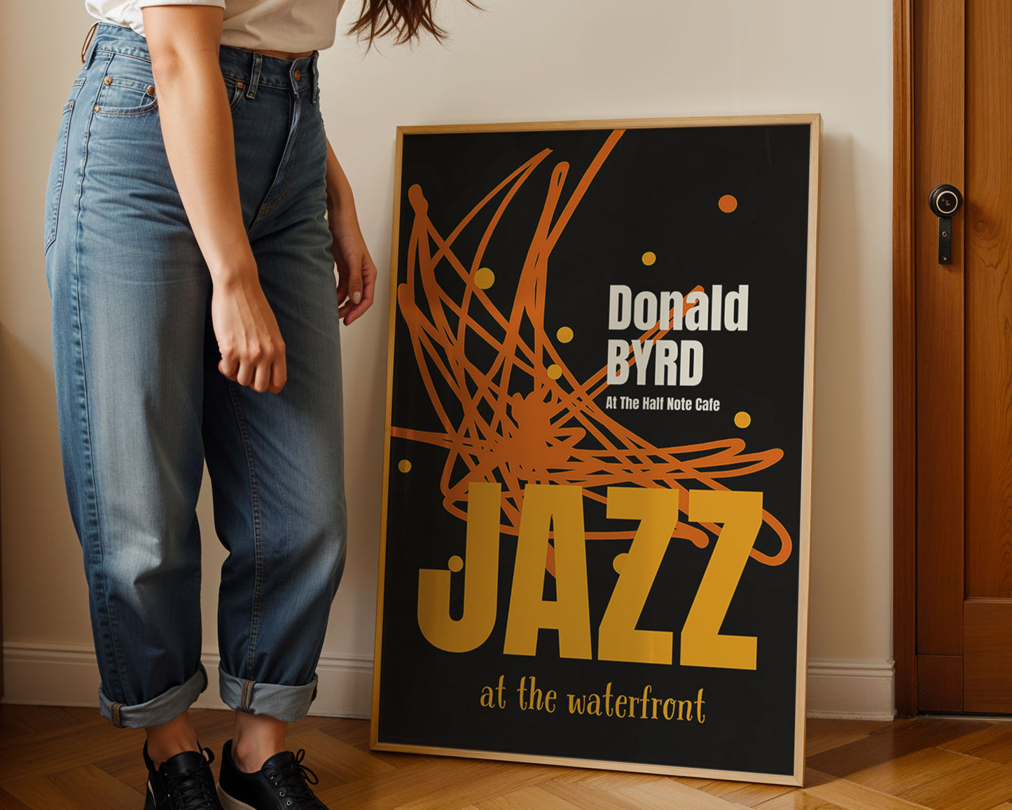 Hipster standing next to a framed poster of Donald Byrd with 'Jazz at the waterfront' text.