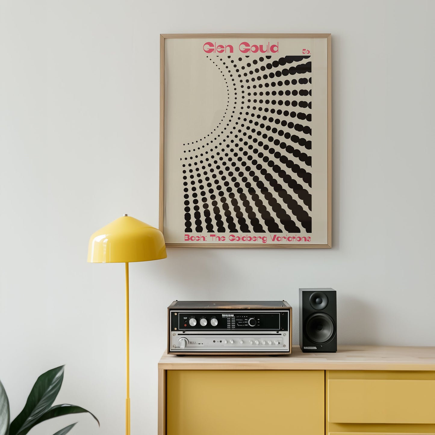 Framed abstract art print on a wall above a yellow cabinet with audio equipment.