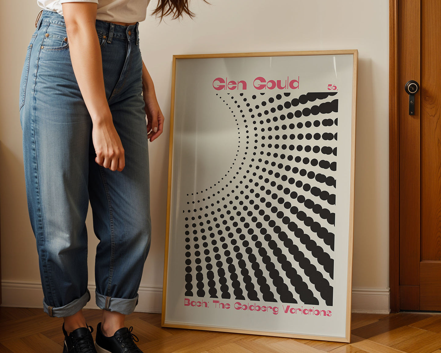 Person standing next to a framed artwork with a geometric design and text on a wall.