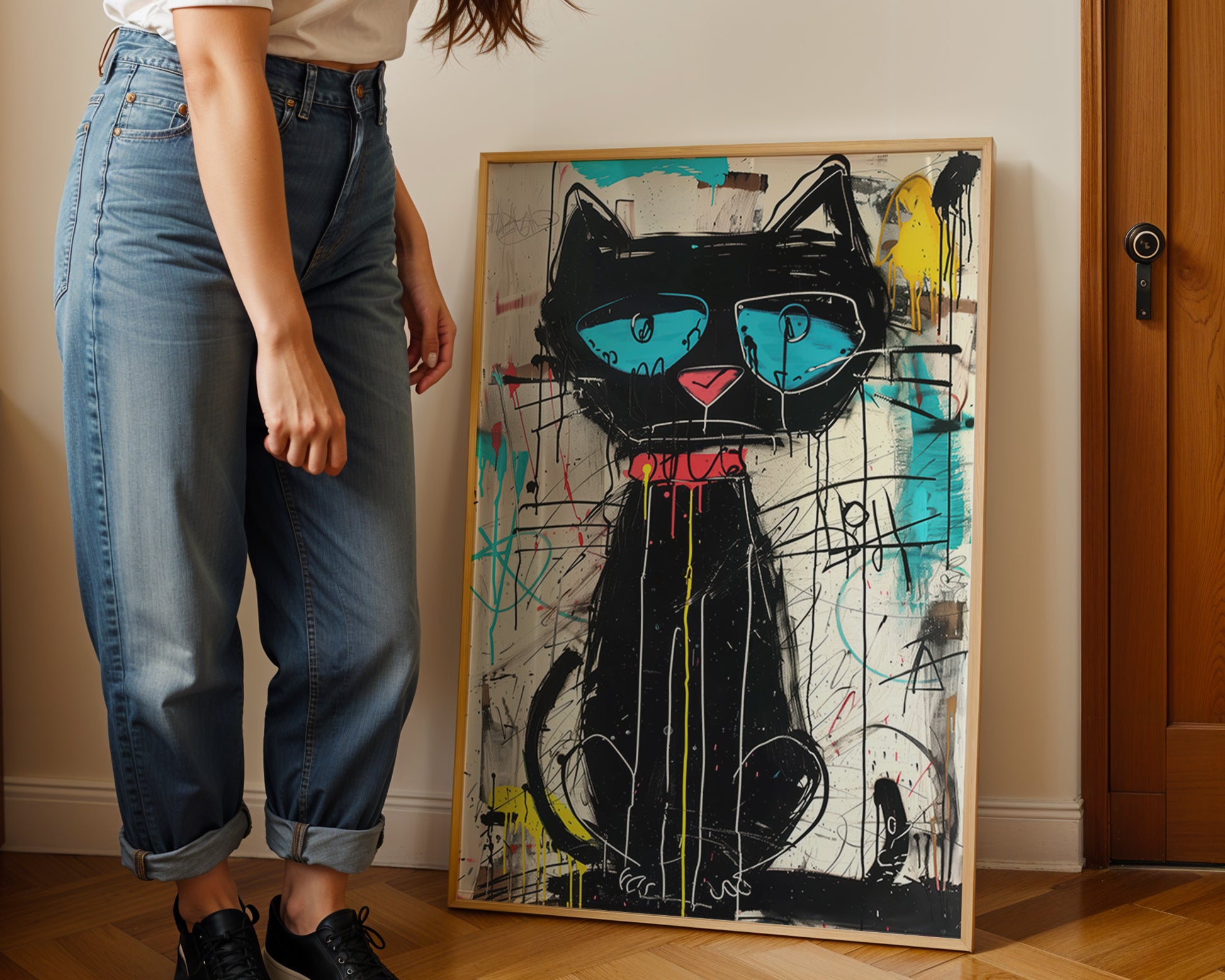 Person standing next to a framed painting of a stylized black cat with blue eyes and a pink nose.